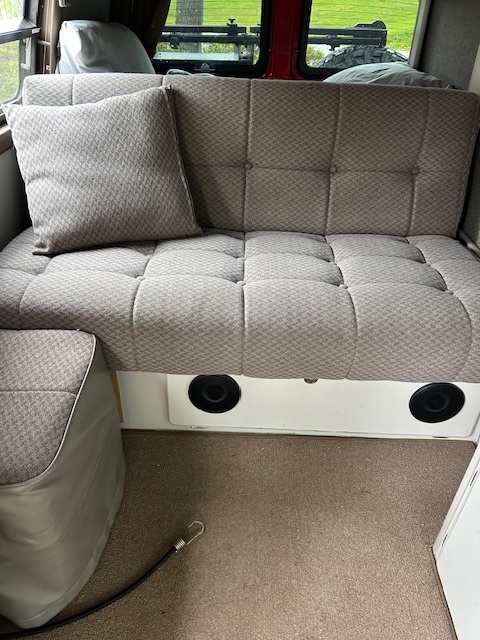 Comfy tufted sofa with a matching pillow and integrated speakers, perfect for relaxing in this RV rental interior.. Chevrolet Express Silverado 3500 4X4 Sportsmobile edition 2008