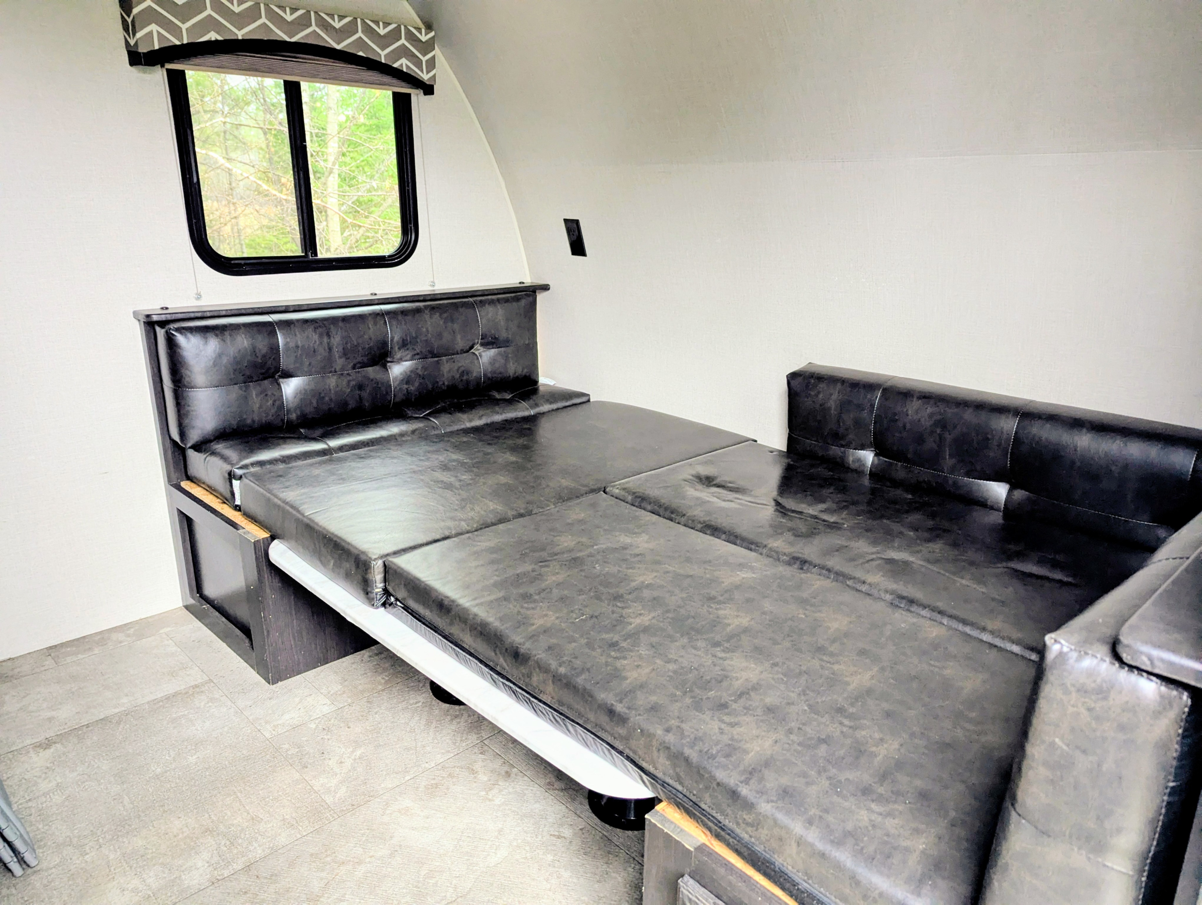 Inside this **rv rental**, a versatile black faux leather dinette easily converts into a spacious sleeping area, perfect for travel.. Sonic Lite 2019