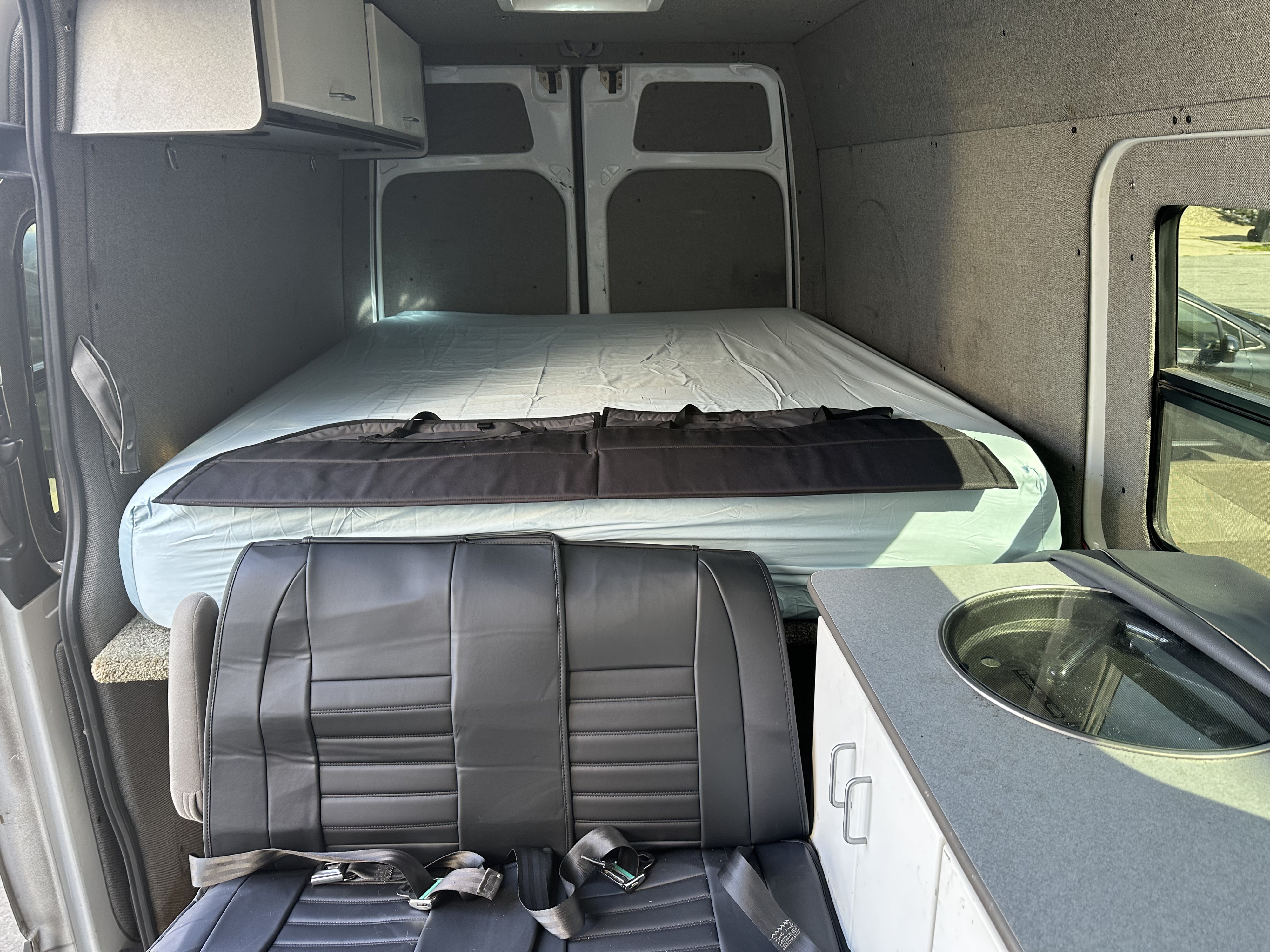 Explore this RV rental's cozy interior: bed, passenger bench seat with belts, and a small counter with a sink.. WDYPE745675164126 Mercedes Sprinter Van 2007