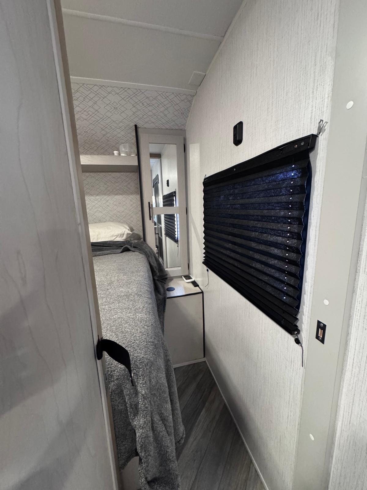 Cozy rv rental bedroom features a bed, mirrored closet, and window blind, offering compact comfort for travel.. Heartland RVs Prowler 2023