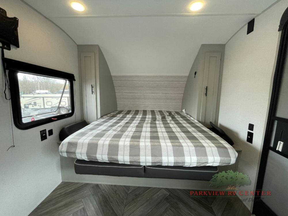 Inside this RV rental is a bright bedroom featuring a plaid bed, window, and compact storage cabinets.. Forest River Salem FSX Plantium 2022