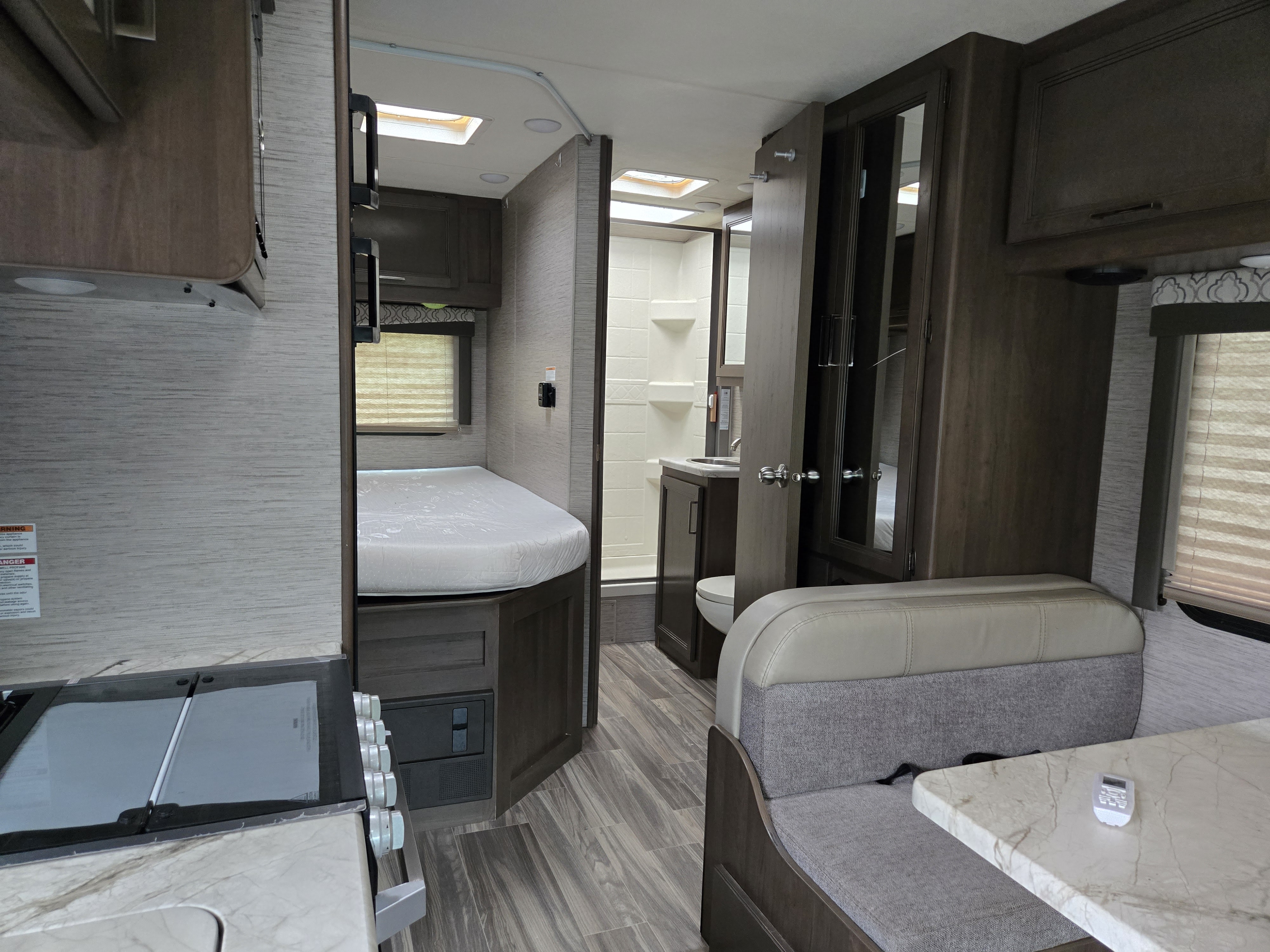 Rv rental interior: A cozy space with a kitchenette, comfortable bed, compact bathroom with shower, and a dinette.. Thor Freedom Elite 2021