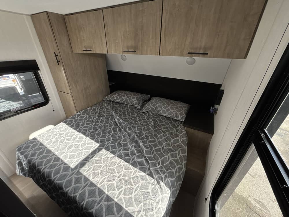Cozy RV rental bedroom featuring a queen bed with modern storage cabinets and windows for natural light.. Forest River Grey Wolf 2026