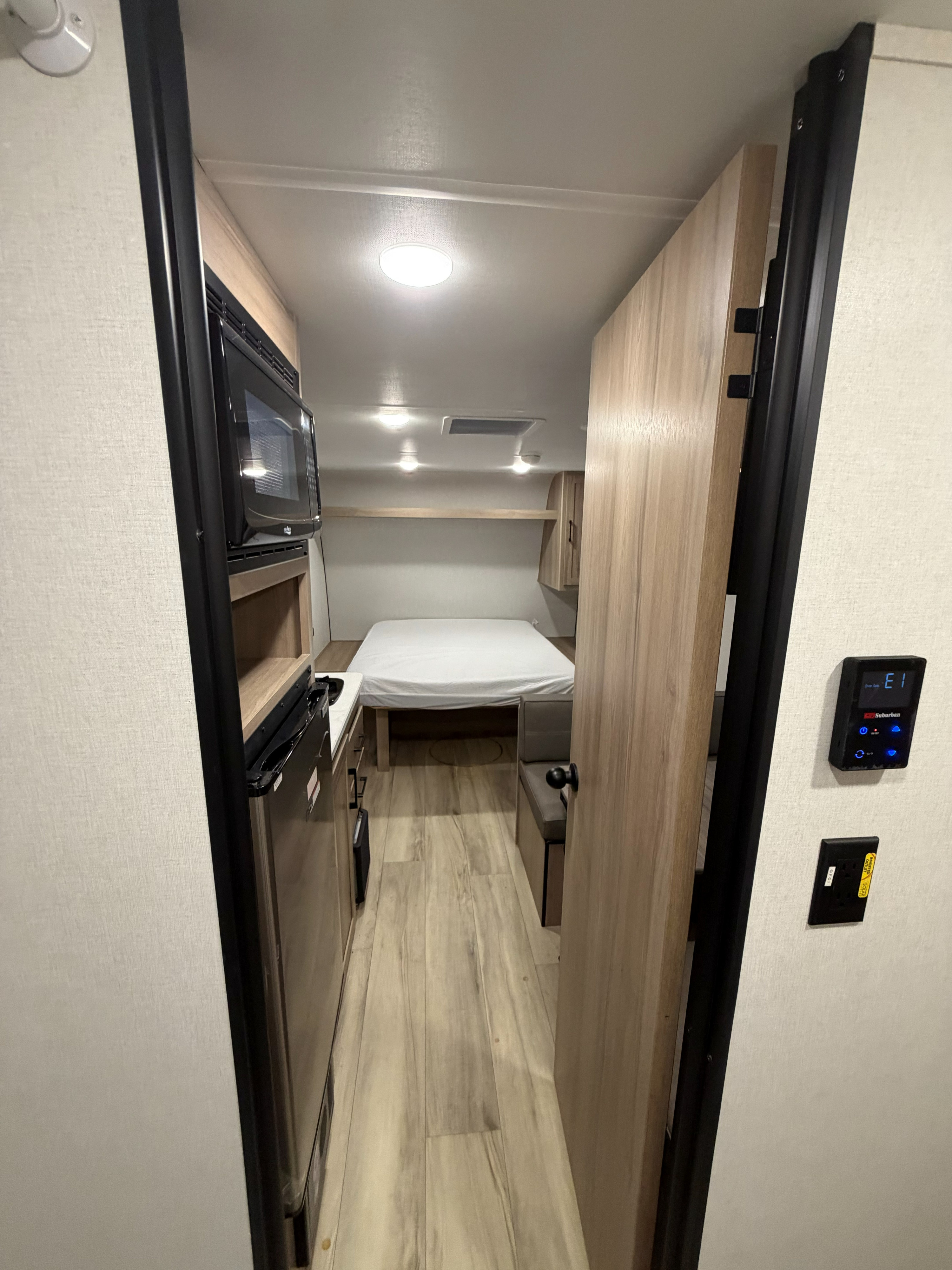 Compact rv rental interior showing a comfortable bed, microwave, and kitchenette, perfect for travel.. Keystone RV Coleman 2025