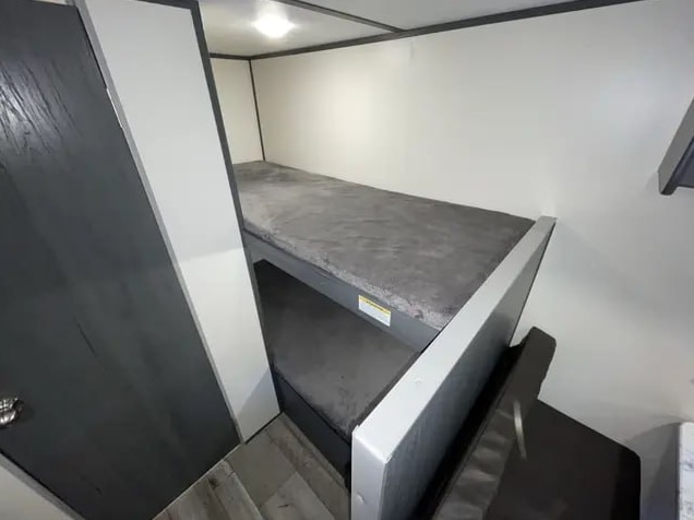 RV rental: Compact bunk beds with dark grey mattresses and wood-look floor in a bright camper interior.. Aspen Trail LE 2022