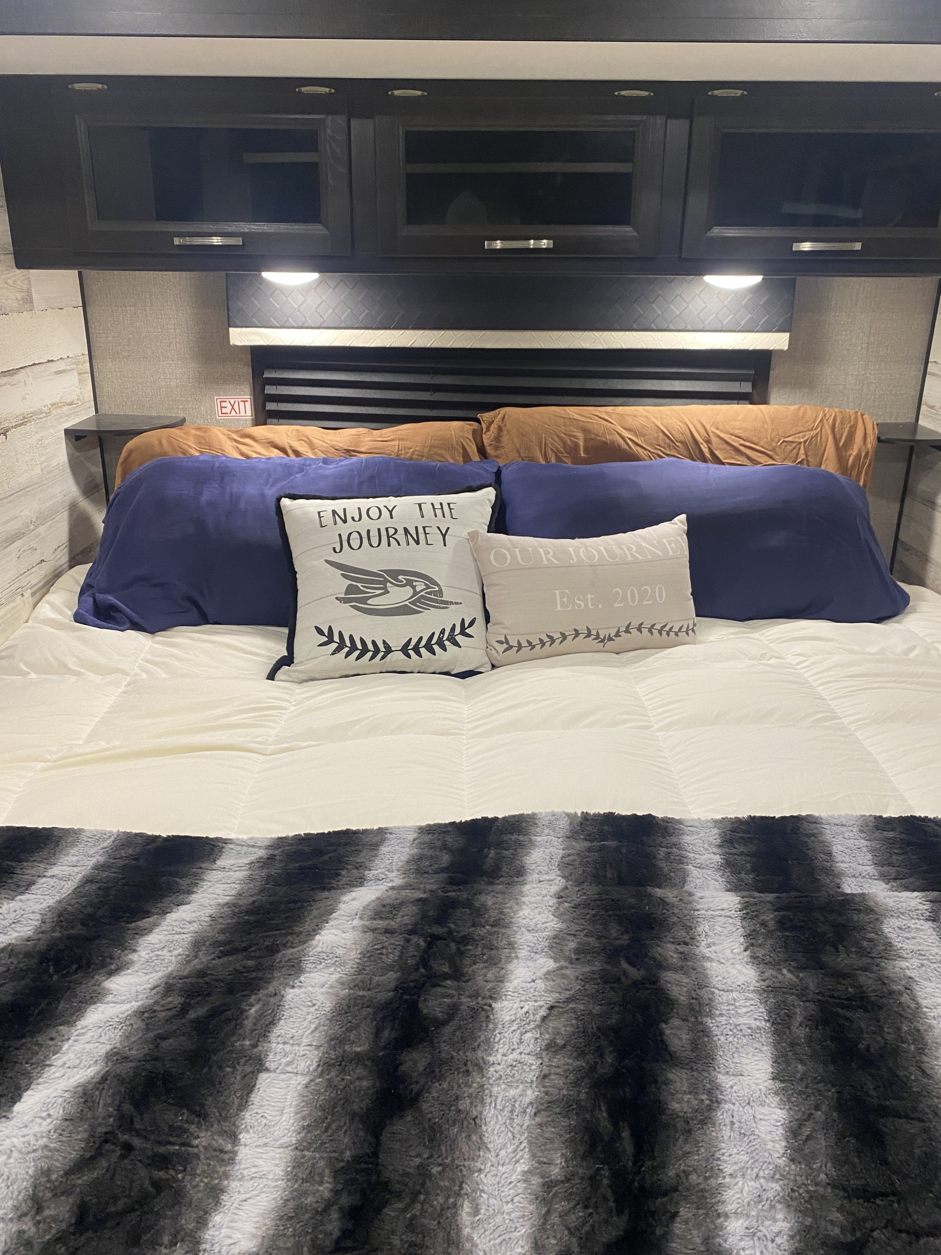 Comfortable rv rental bedroom with a cozy bed, overhead cabinets, and decorative pillows, ready for your next adventure.. Jayco White Hawk 2020