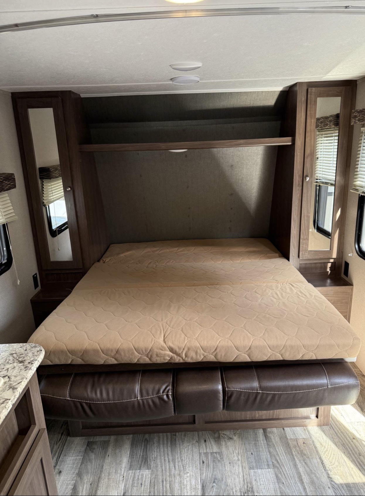 RV rental: This RV's bedroom has a bed that folds over a couch, flanked by mirrored storage units, in a camper interior.. Keystone RV Hideout 2018