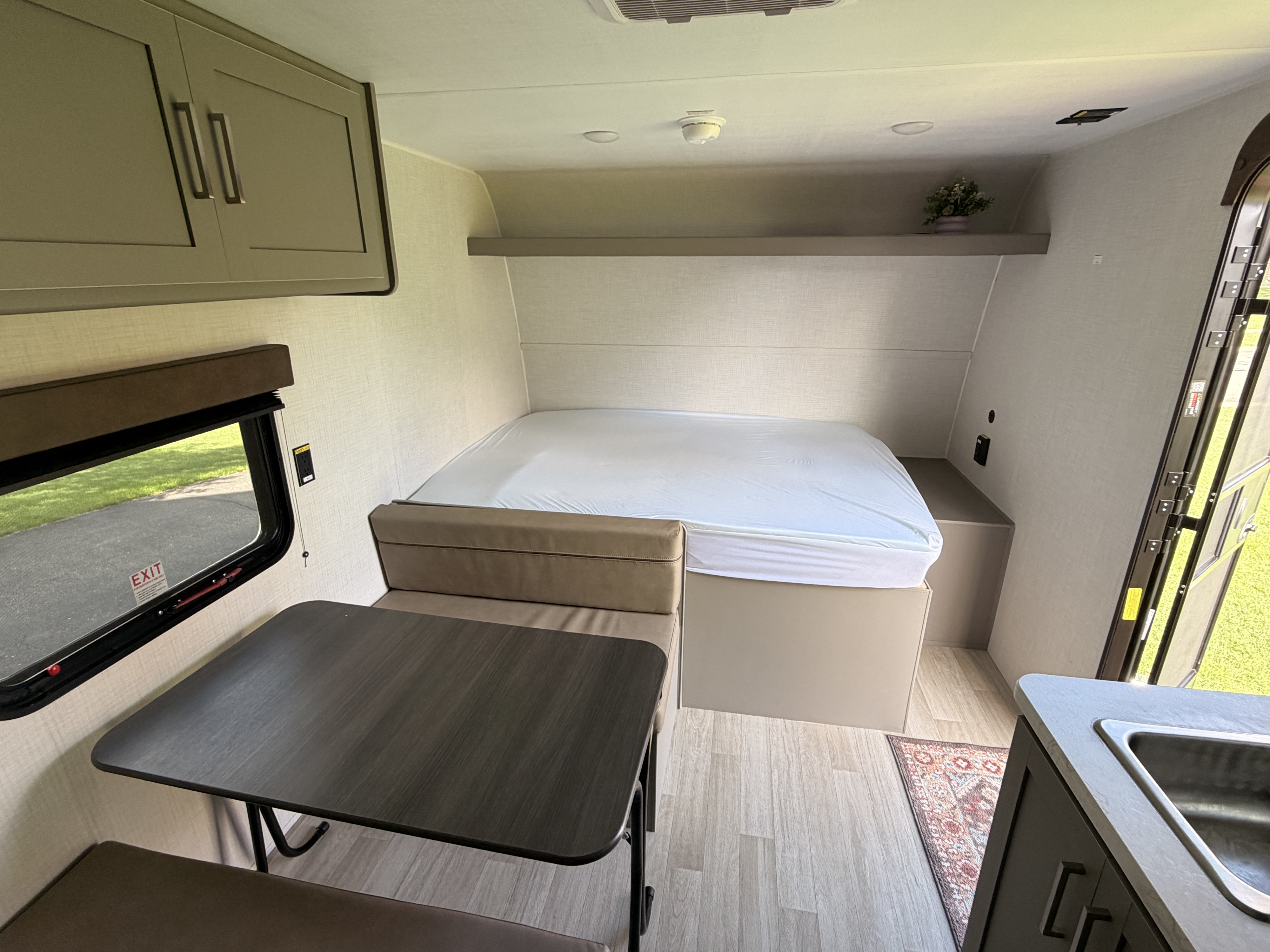 Bright RV rental interior: a compact living space featuring a bed, dinette, and small sink area.. Keystone Hideout Sport 175BH 2026