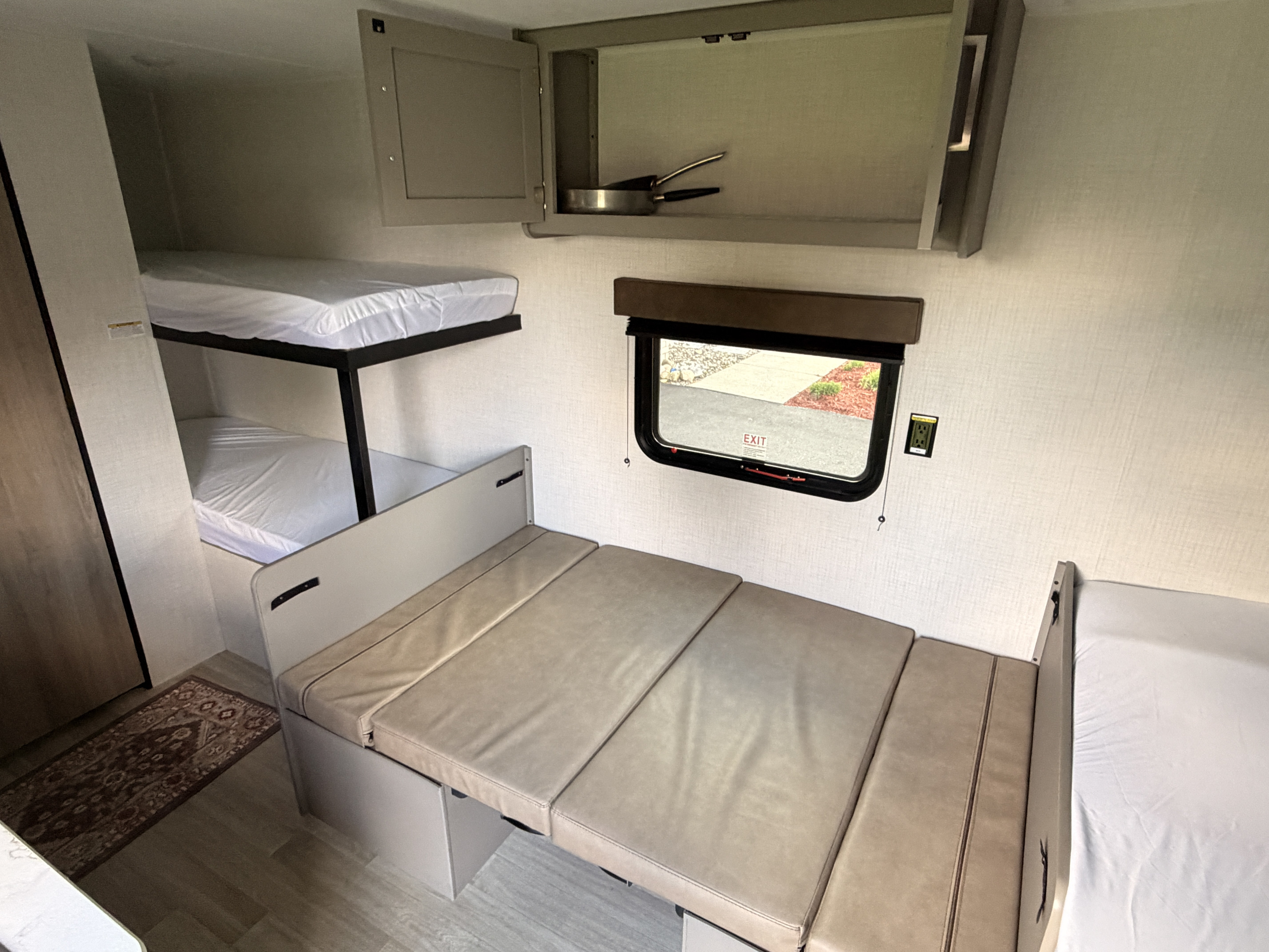 This rv rental shows the cozy camper interior with bunk beds, a convertible dinette, window, and overhead cabinet.. Keystone Hideout Sport 175BH 2026