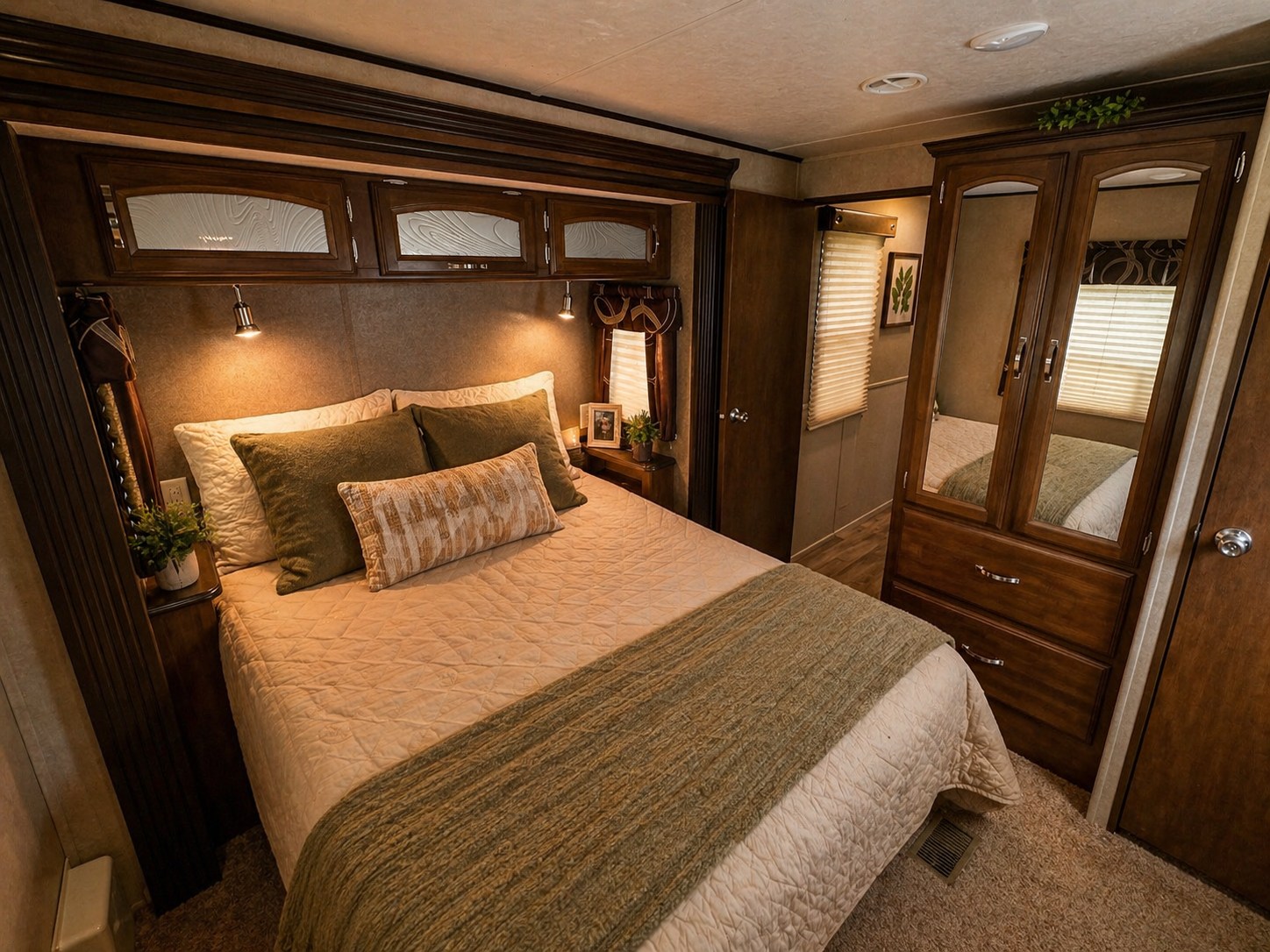 Cozy RV rental bedroom with a bed, overhead storage, and mirrored wardrobe.. Forest River Wildwood DLX 2016