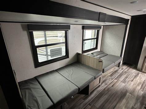 RV rental interior features two modern grey beds/couches, windows, wood-look floor, and dark trim, ready for travel.. Starcraft Autumn Ridge 2021