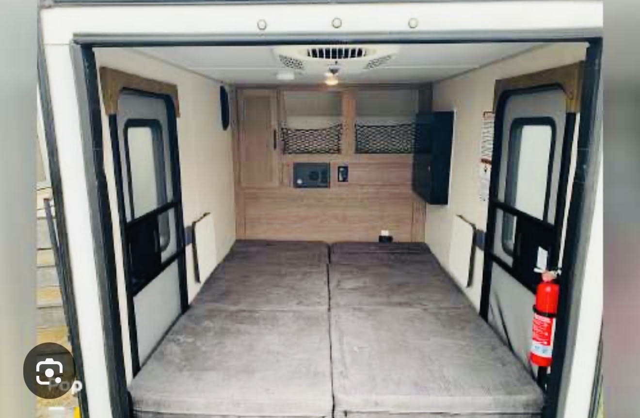 Explore this cozy rv rental interior featuring two comfy beds, overhead storage, and a visible fire extinguisher.. Forest river No boundaries 10.6 2019