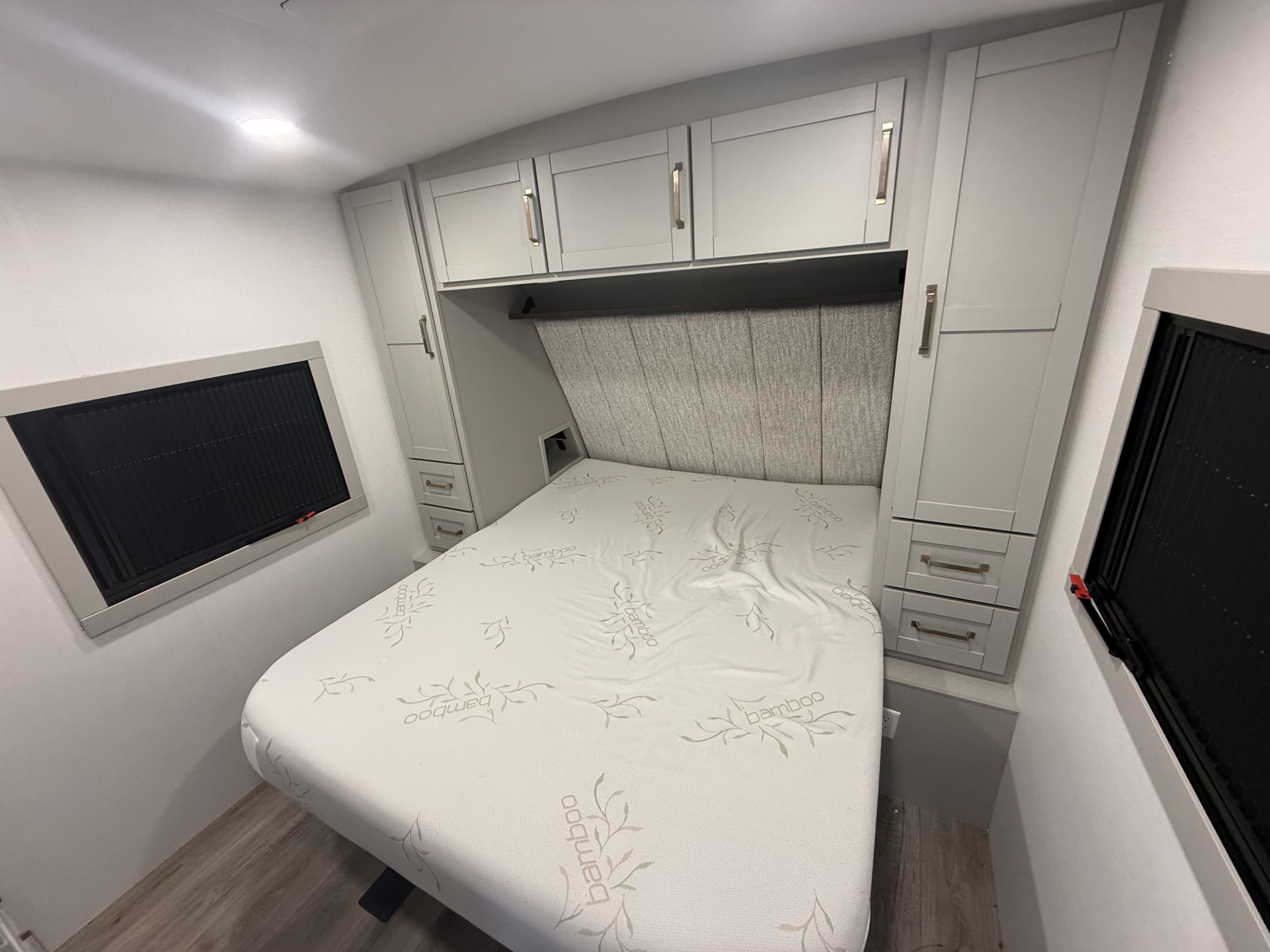 RV rental bedroom: light gray cabinets, padded headboard, Bamboo mattress, side storage, and dark windows.. Brinkley RV Model Z Air 2025
