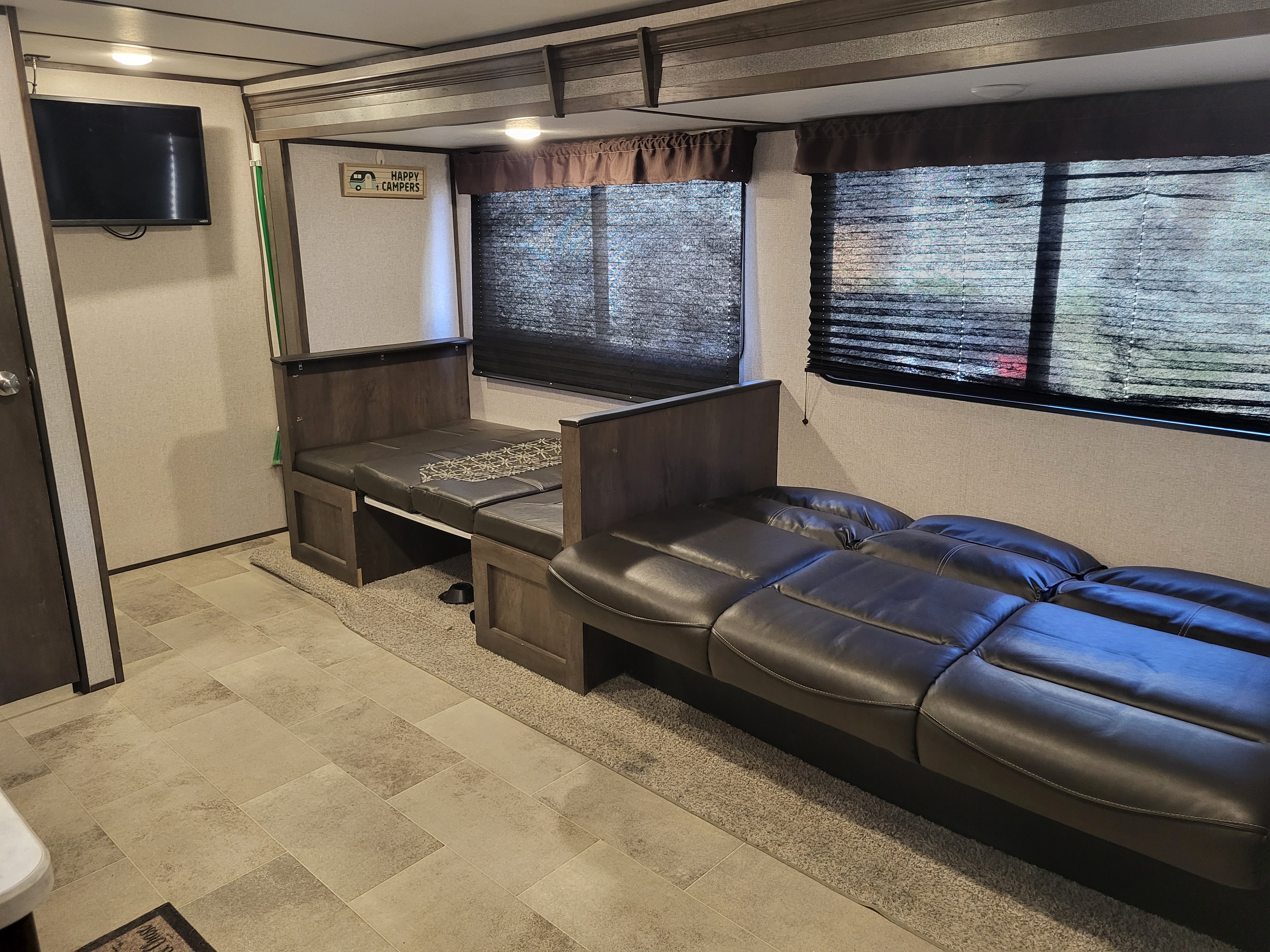 Cozy rv rental interior with convertible beds/seating, a TV, and dark blinds. Ideal for comfortable travel.. Keystone RV Coleman Lantern 2020