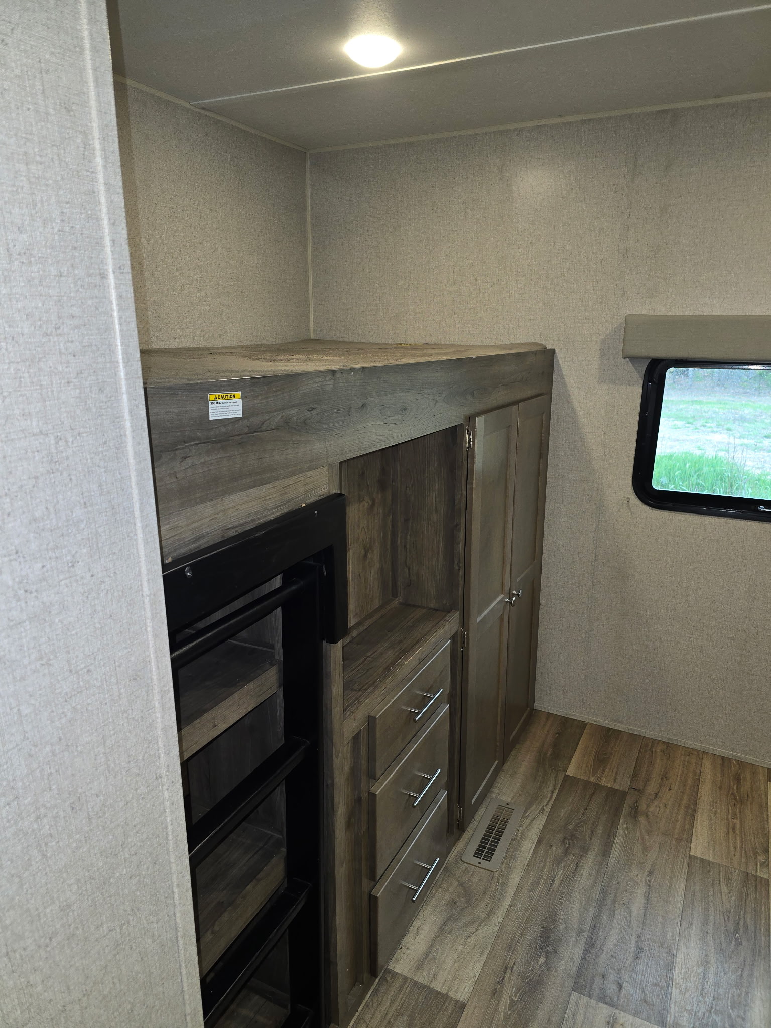 RV rental bedroom with a built-in bunk bed, ladder access, storage cabinetry, drawers, and a view from the window.. Dutchmen Aspen Trail 2019