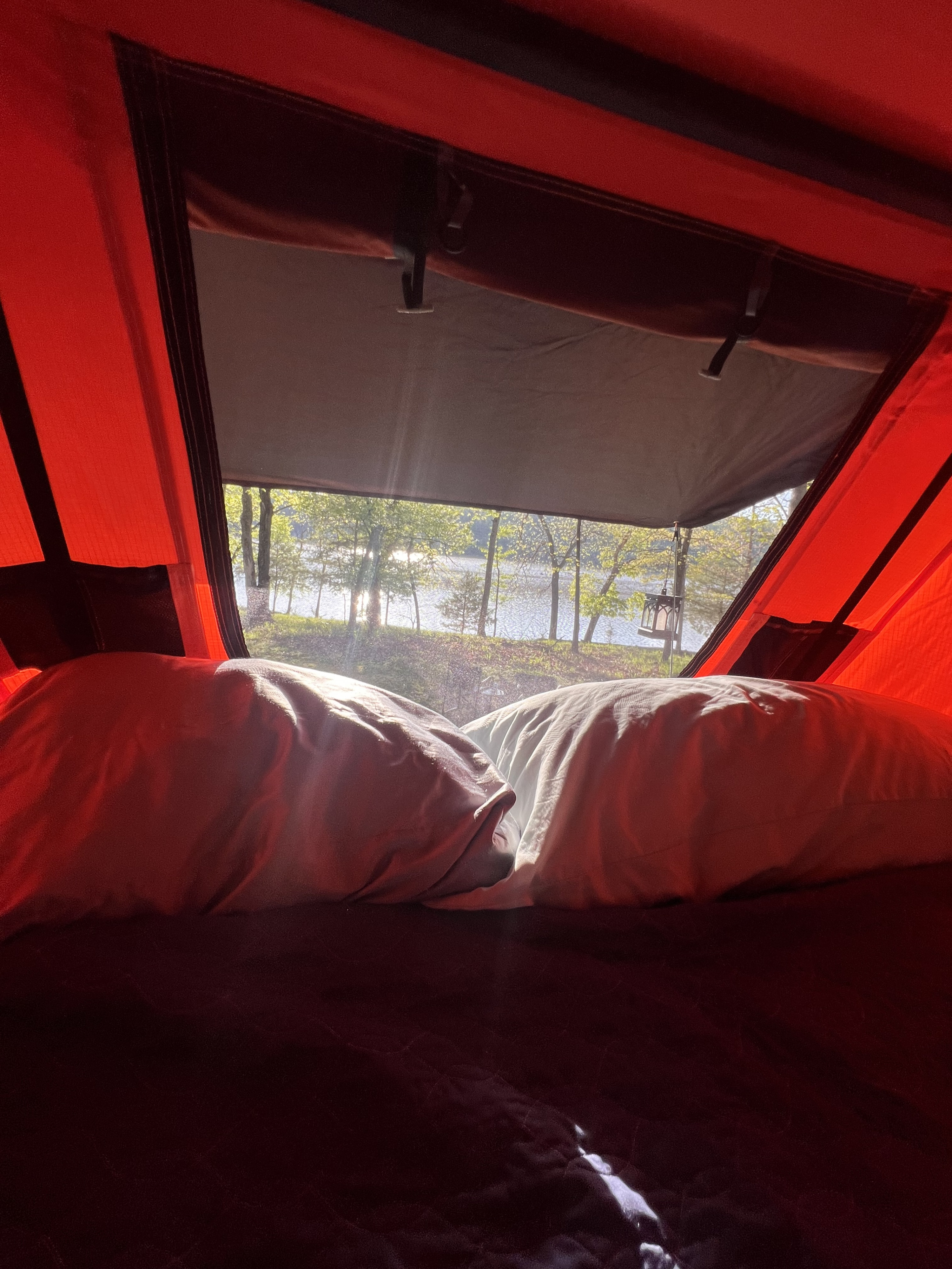 RV rental view: Waking up to a serene lakeside view from inside a cozy camper, with pillows in the foreground.. American Trailer Suburu Forester 2007