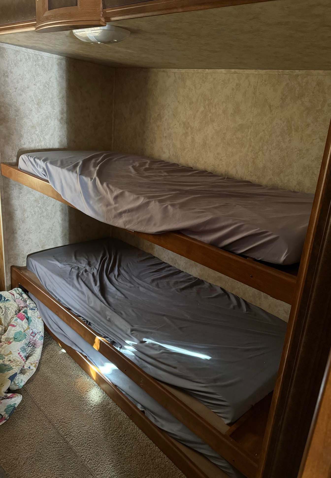 Compact RV rental bunk beds with grey sheets offer a cozy sleeping area, perfect for family travel adventures.. Keystone RV Bullet Premier Ultra 2011
