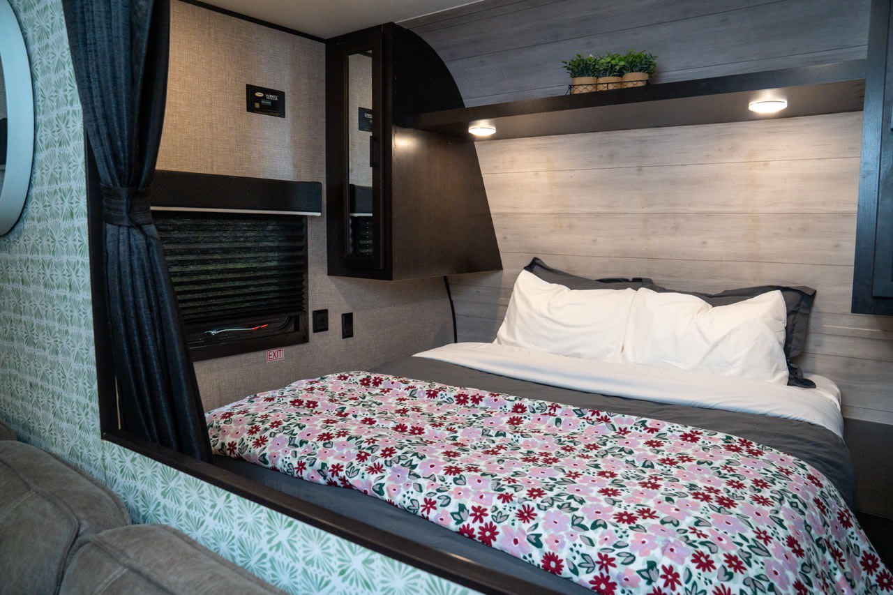 Cozy RV rental bedroom with floral bedding, window, and shelf. Ideal for a comfortable travel trailer getaway.. Jayco Jay Flight SLX 2021