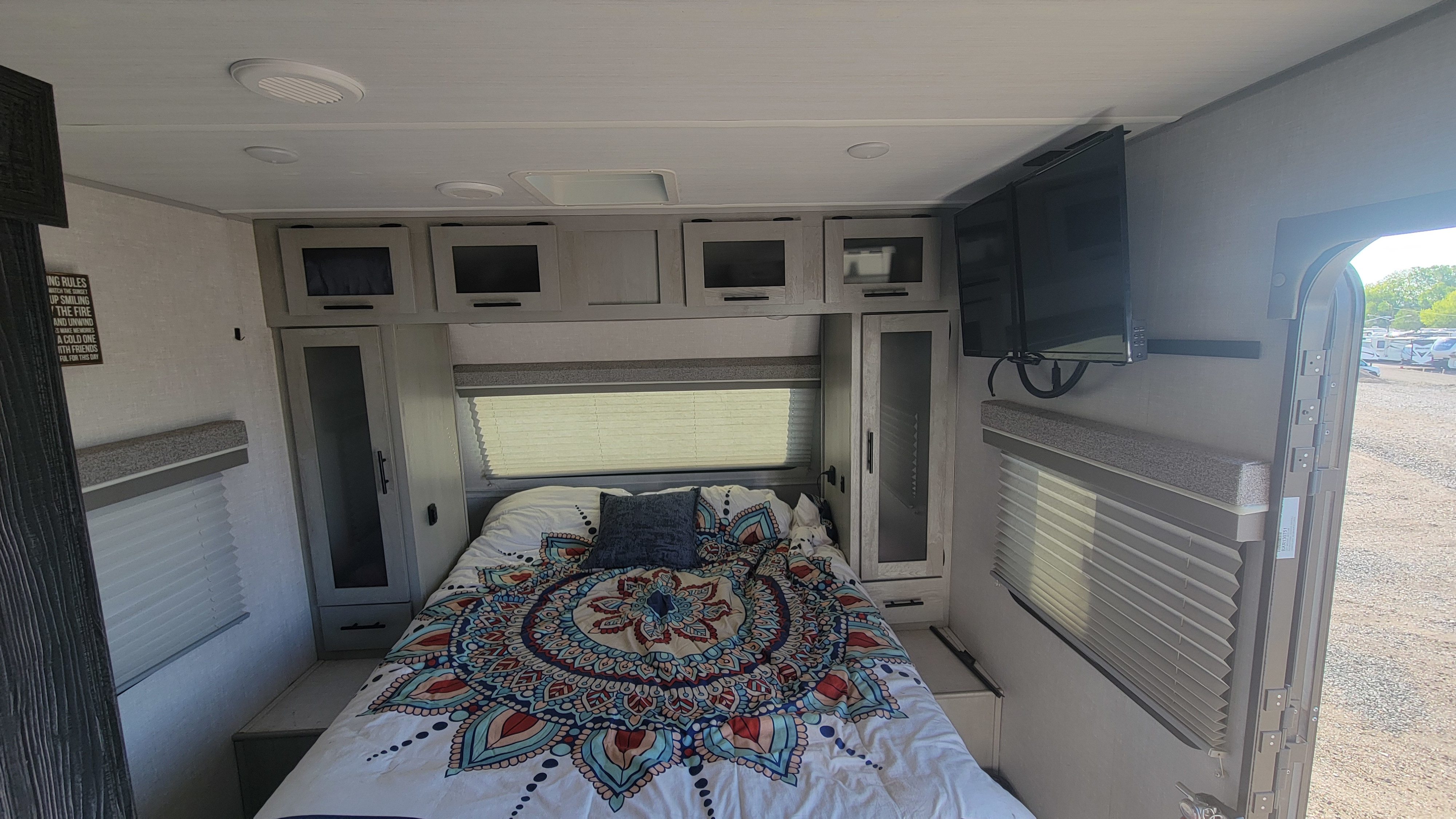 Cozy RV rental bedroom with a colorful mandala bed, TV, and ample storage, perfect for your comfortable travels.. Forest River Ibex 2021