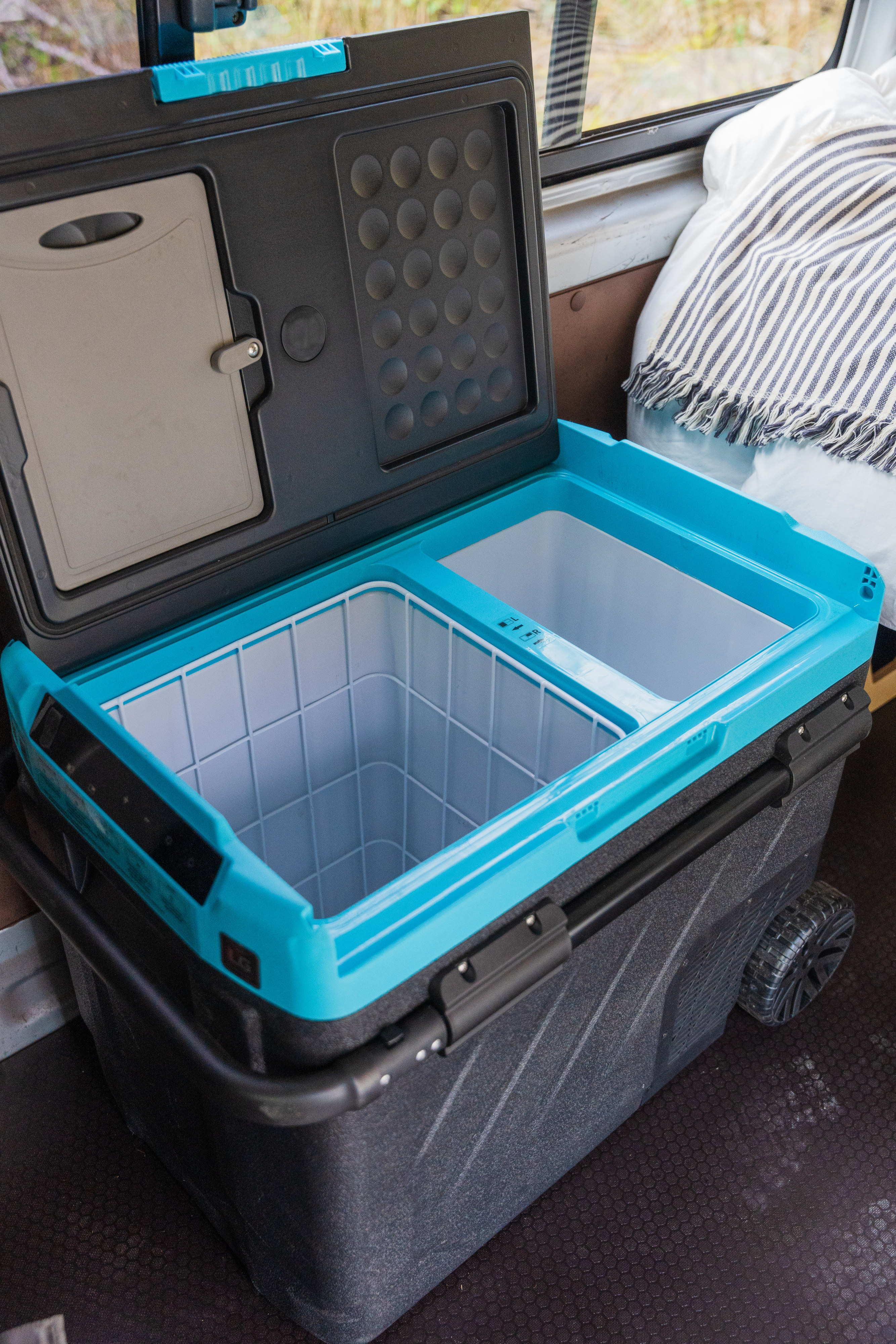 Dual-zone electric cooler with open lid & built-in cutting board inside an rv rental, ready for travel & camping.. Toyota Hiace 2005