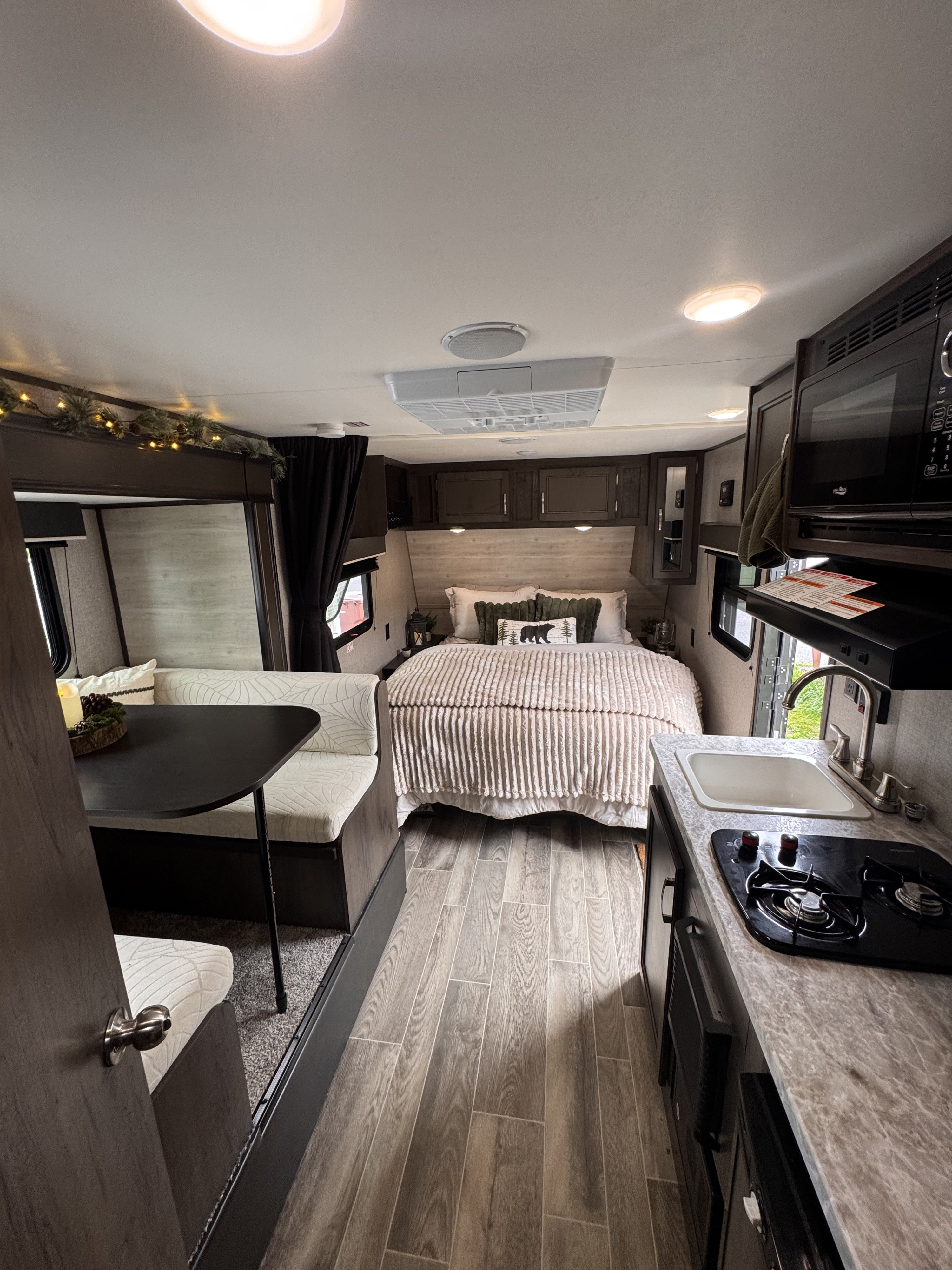 This cozy rv rental interior offers a snug bedroom with a bear pillow, a functional kitchen, and a comfortable dinette setup.. Jayco Jay Flight SLX 2021