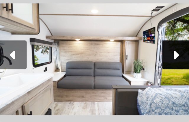 Cozy rv rental interior: gray sofa bed, kitchen sink, window view, and wall-mounted TV.. Gulf Stream Grand River 2025