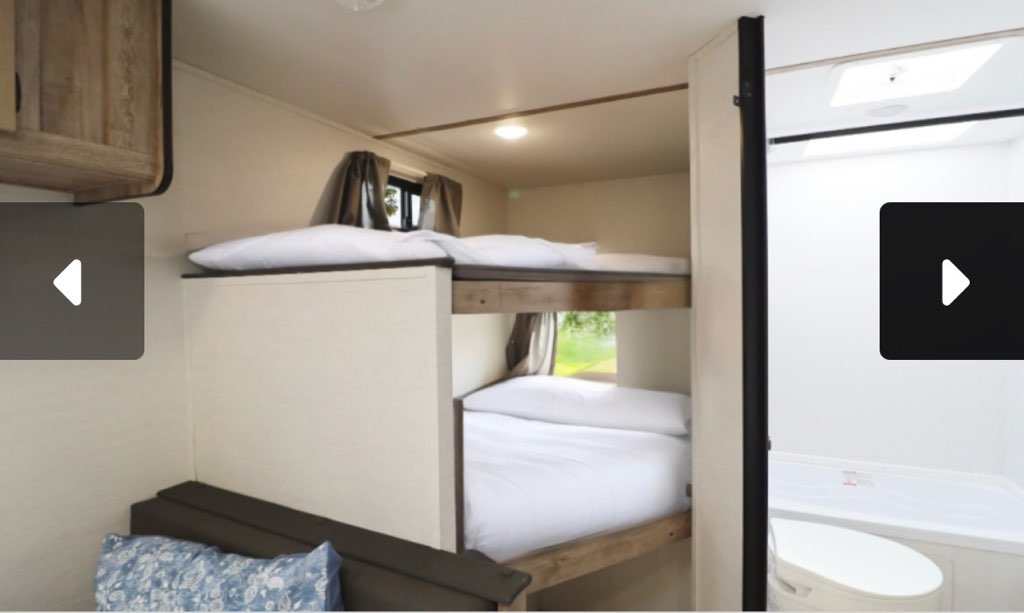 Cozy RV rental interior with bunk beds and a compact bathroom, ideal for family travel.. Gulf Stream Grand River 2025