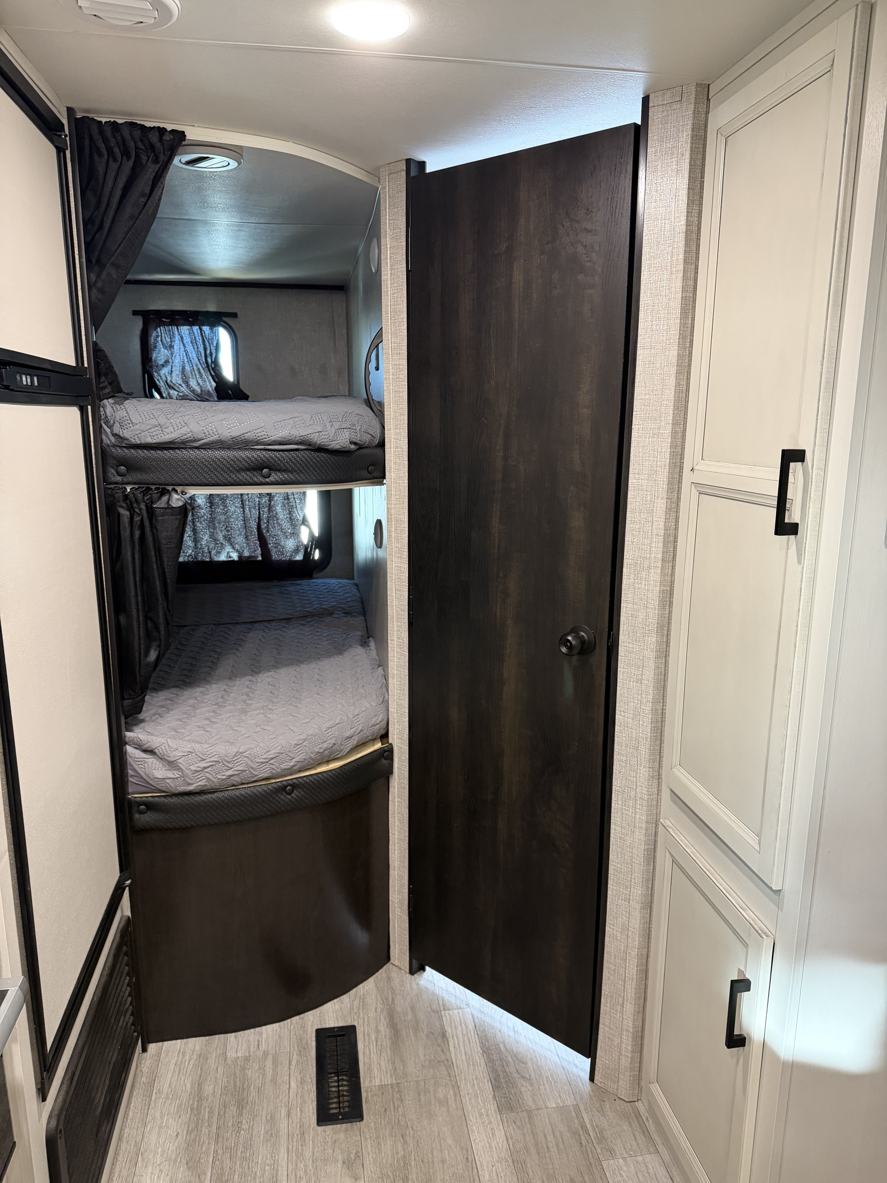 This modern RV rental features cozy bunk beds and storage cabinets, offering practical sleeping and storage solutions in a travel trailer.. Jayco Jay Flight Baja Edition 2023