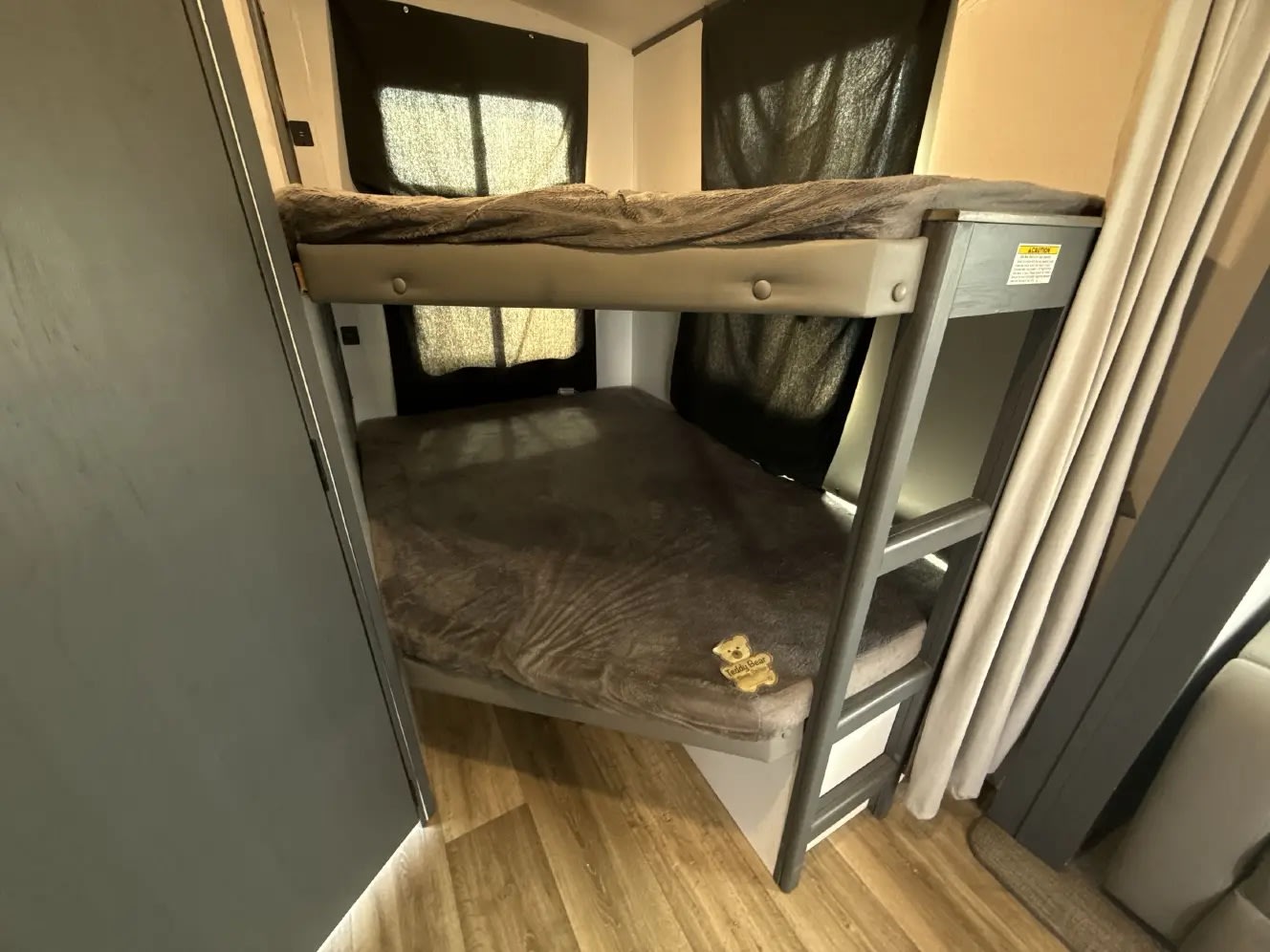 This RV rental features cozy bunk beds with soft gray blankets and dark window blinds, ideal for family travel.. Keystone RV Bullet Ultra Lite 2022