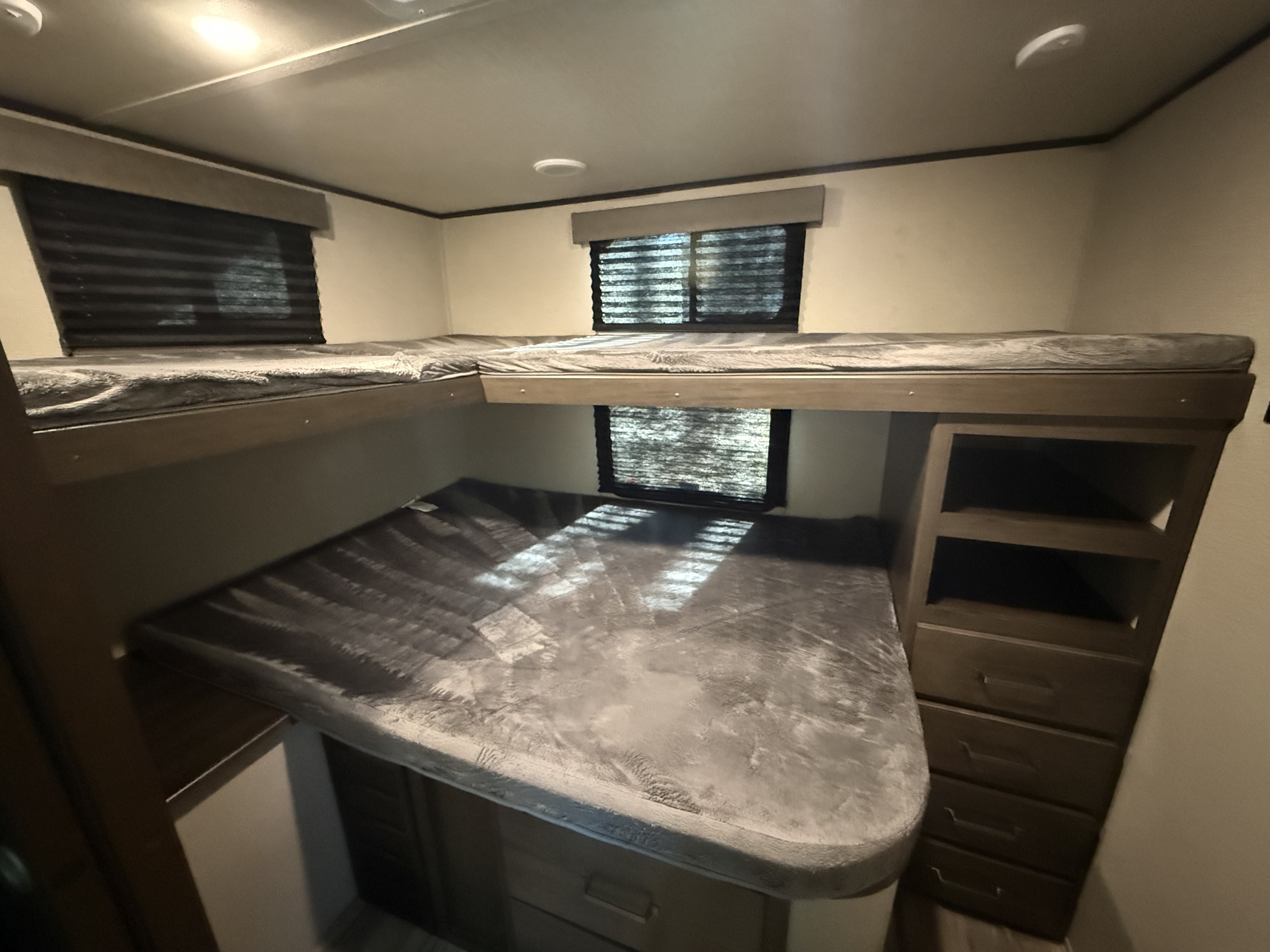 RV rental bunk room with two upper and one lower bunk bed, built-in storage, and window blinds for privacy.. Grand Design Transcend Xplor 2022