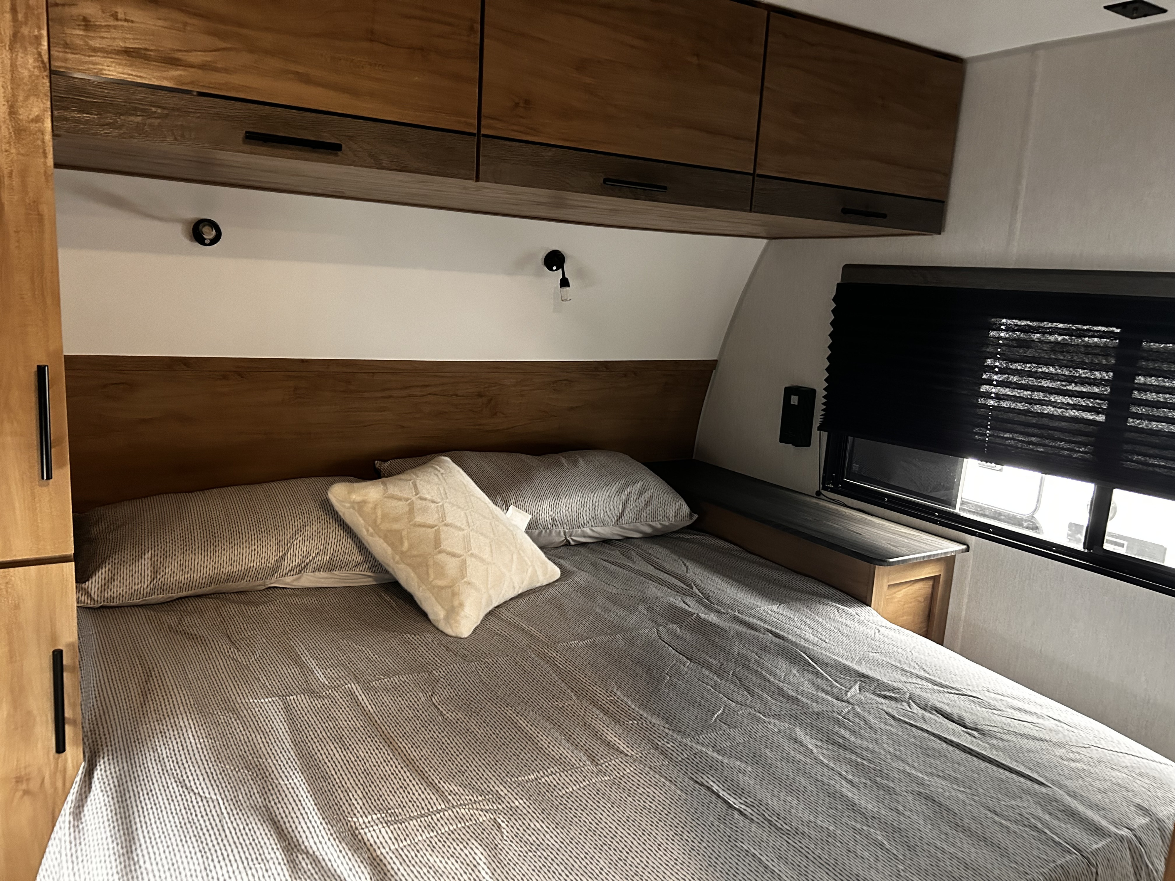 RV rental bedroom: comfy bed, wooden overhead storage, and window with blackout blinds for a good night's sleep.. Forest River Campsite Reserve 2024