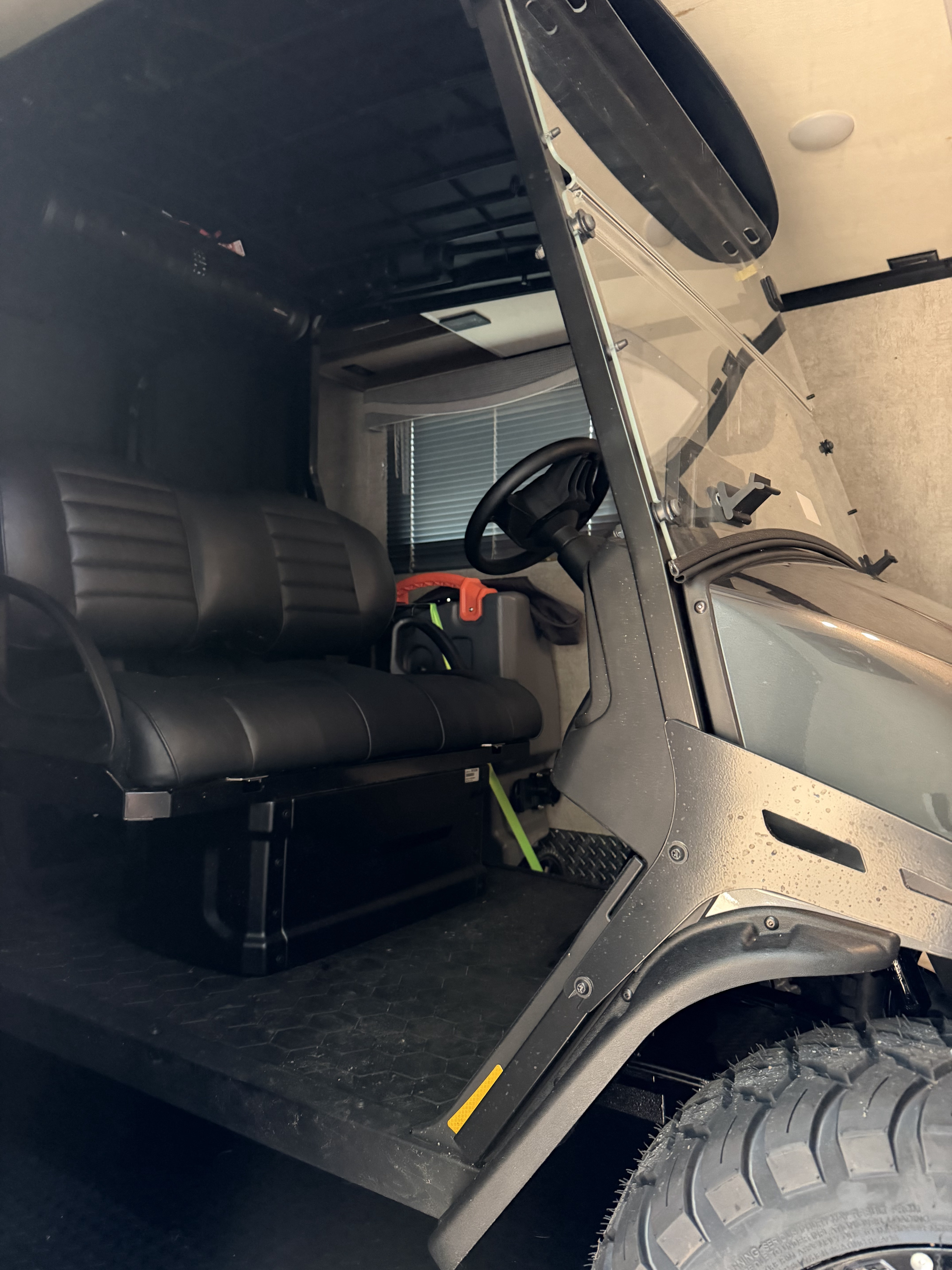 A golf cart with black seats and rugged tires, safely stored inside an RV rental's toy hauler, ready for adventure.. Thor Outlaw 2022