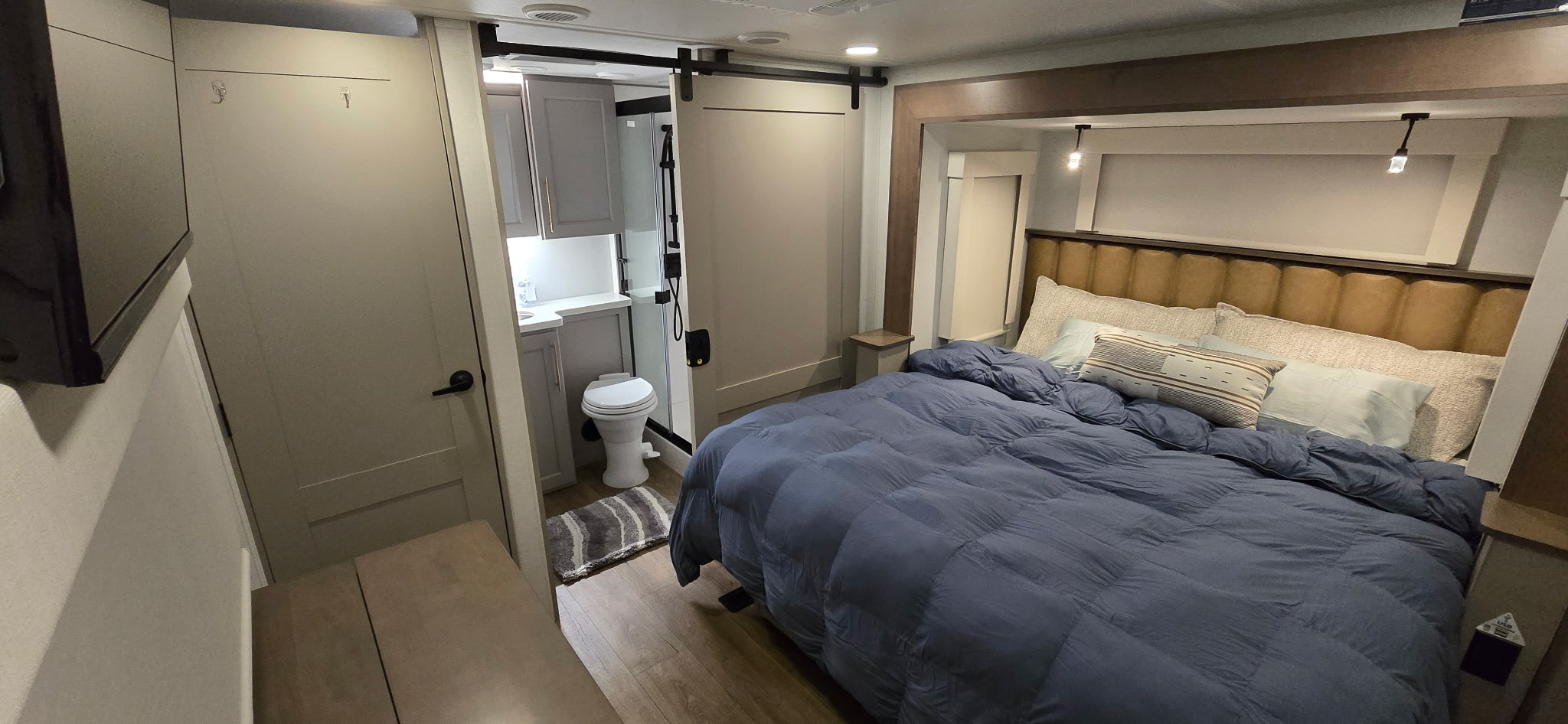 Modern RV rental bedroom and compact bathroom with barn doors, offering cozy travel comfort in a stylish interior.. Alliance Paradigm 2026