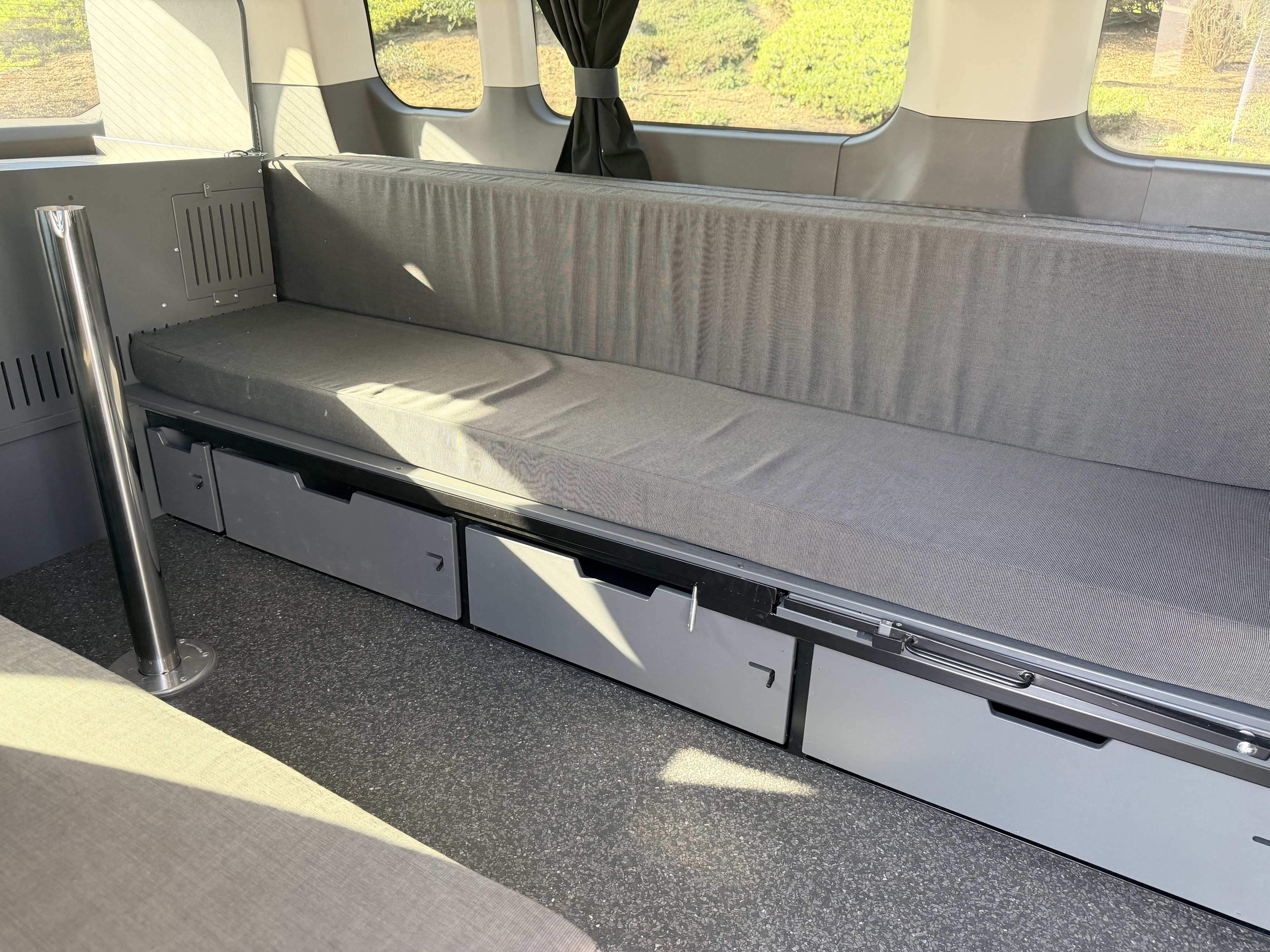 RV rental camper van: efficient interior with a long bench seat, storage drawers, and bright windows. Ideal for travel.. Ford Transit 2023