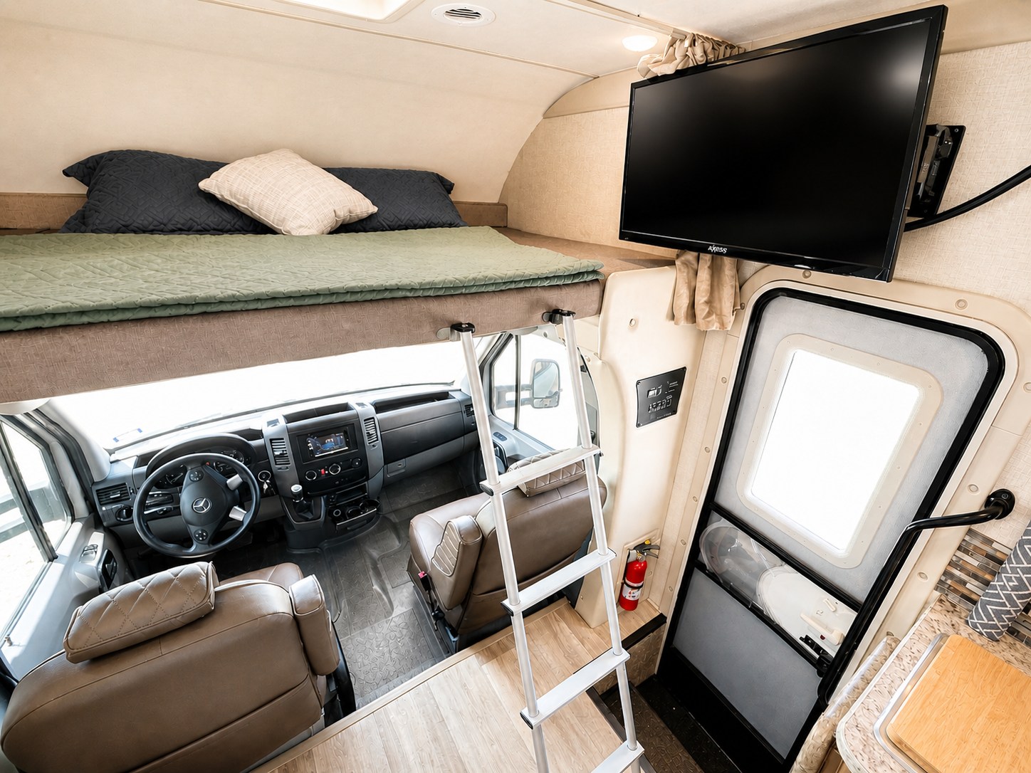 Inside this rv rental: overhead bunk bed, driver's cockpit, wall-mounted TV, and entrance door. A functional motorhome interior.. Thor Four Winds 2018