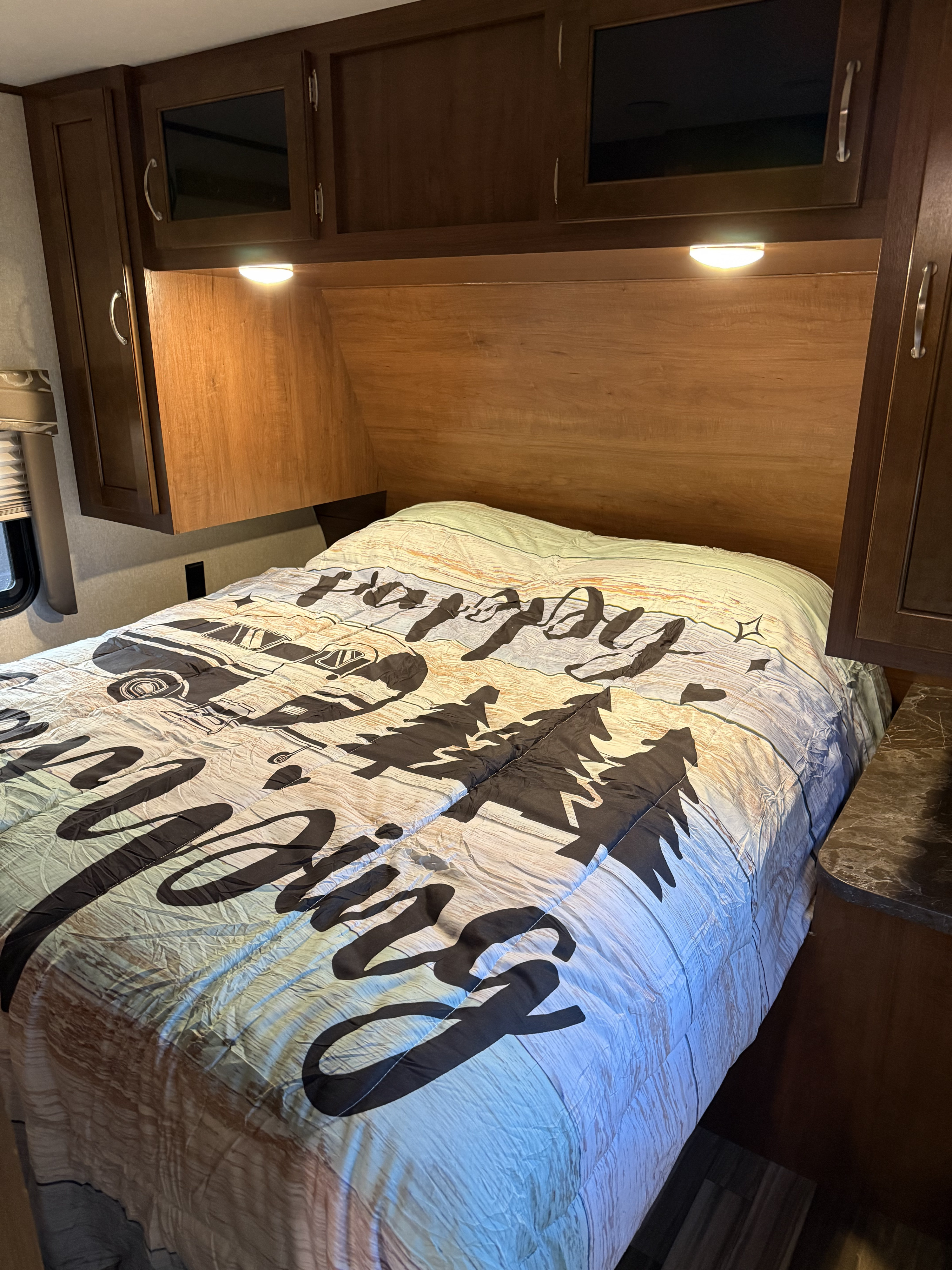 This cozy rv rental bedroom features a comfortable camper bed with a nature-themed comforter, overhead storage, and reading lights.. Jayco Jay Flight 2017