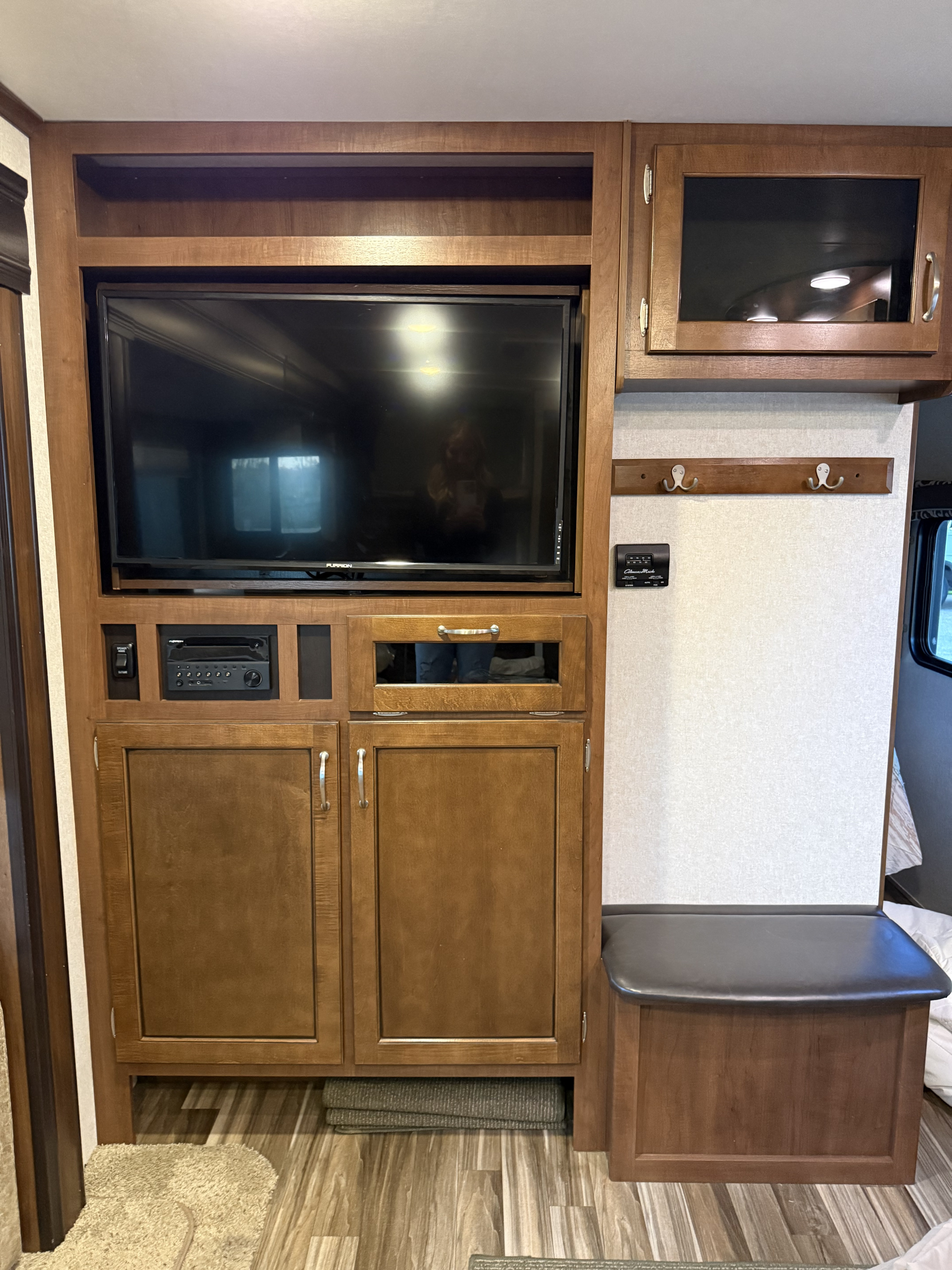 RV rental interior: Wooden entertainment center with TV, stereo, cabinets, coat hooks, and a padded bench seat.. Jayco Jay Flight 2017
