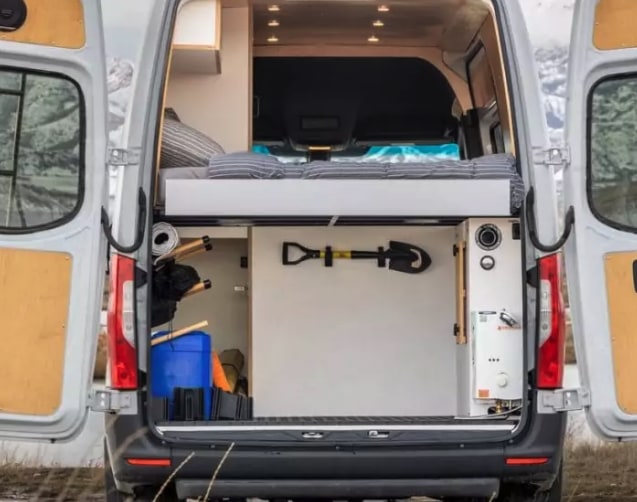 Explore this RV rental van's efficient rear storage: raised bed, shovel, gear, & water heater for adventure.. Mercedes-Benz Sprinter 2023