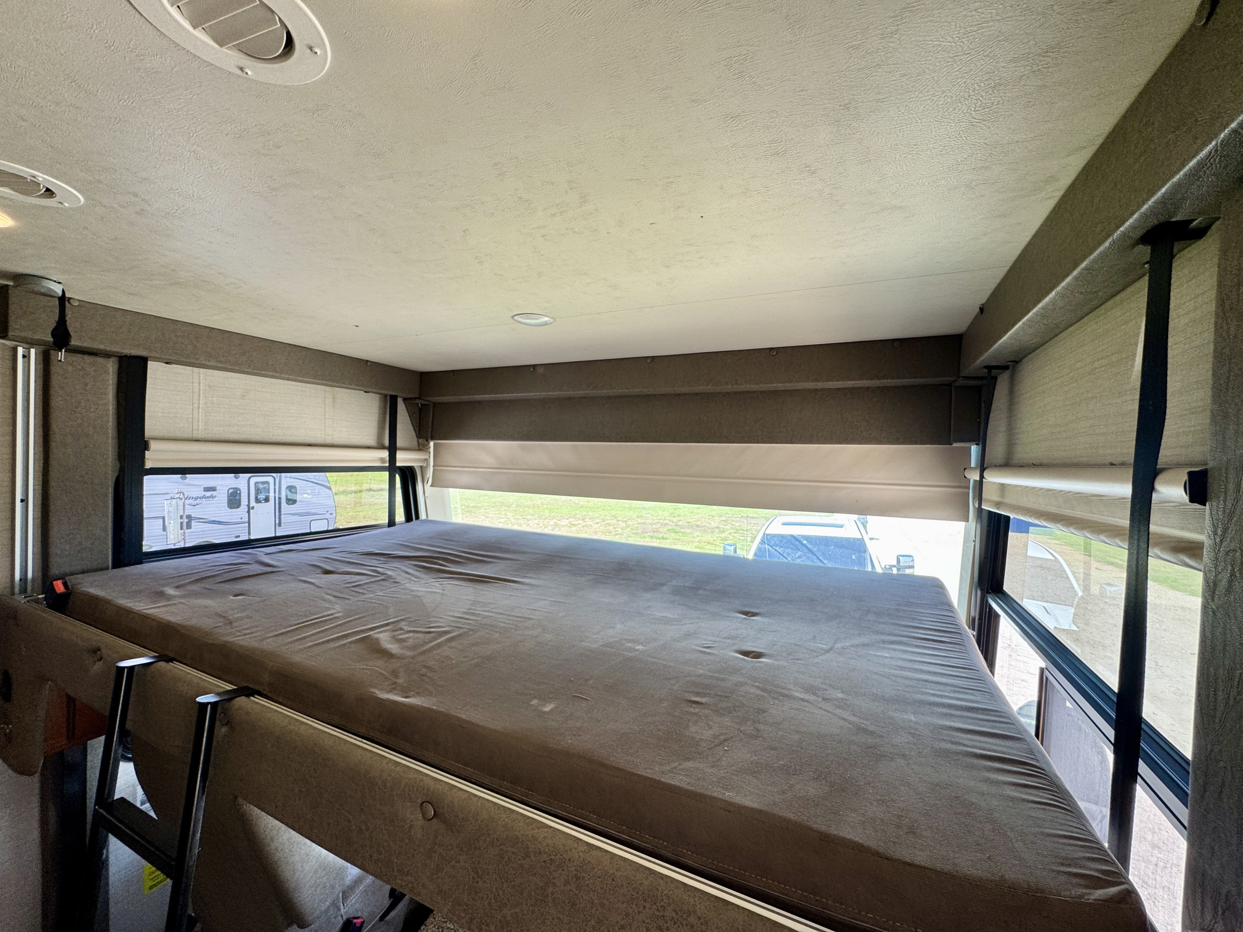 Spacious overhead bunk in an rv rental, featuring a mattress, ladder, windows, and safety belt for secure travel.. Jayco Alante 2017
