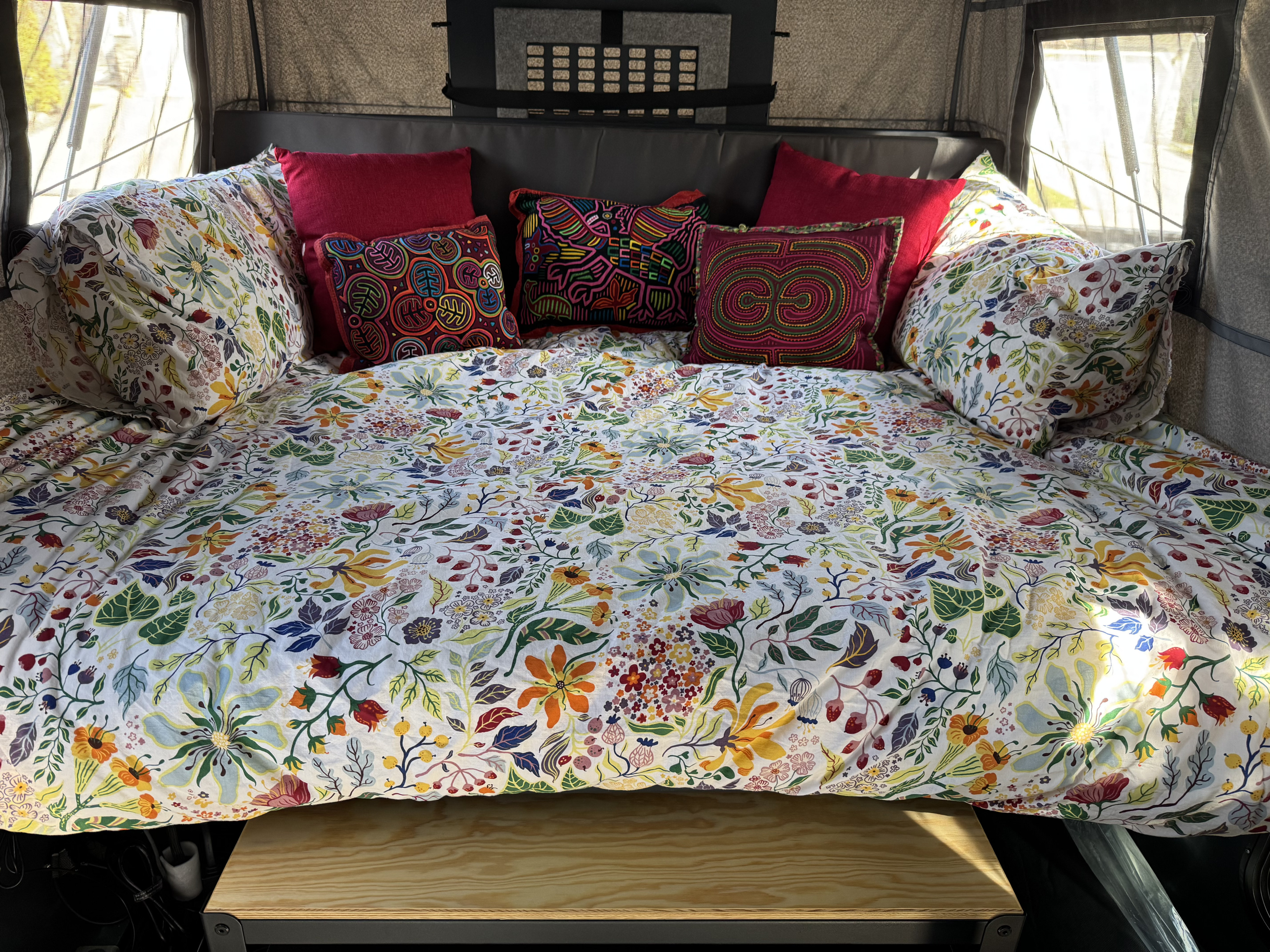 Cozy RV rental bed with vibrant floral duvet cover and colorful patterned pillows, offering a comfortable stay.. Toyota Tundra 2025
