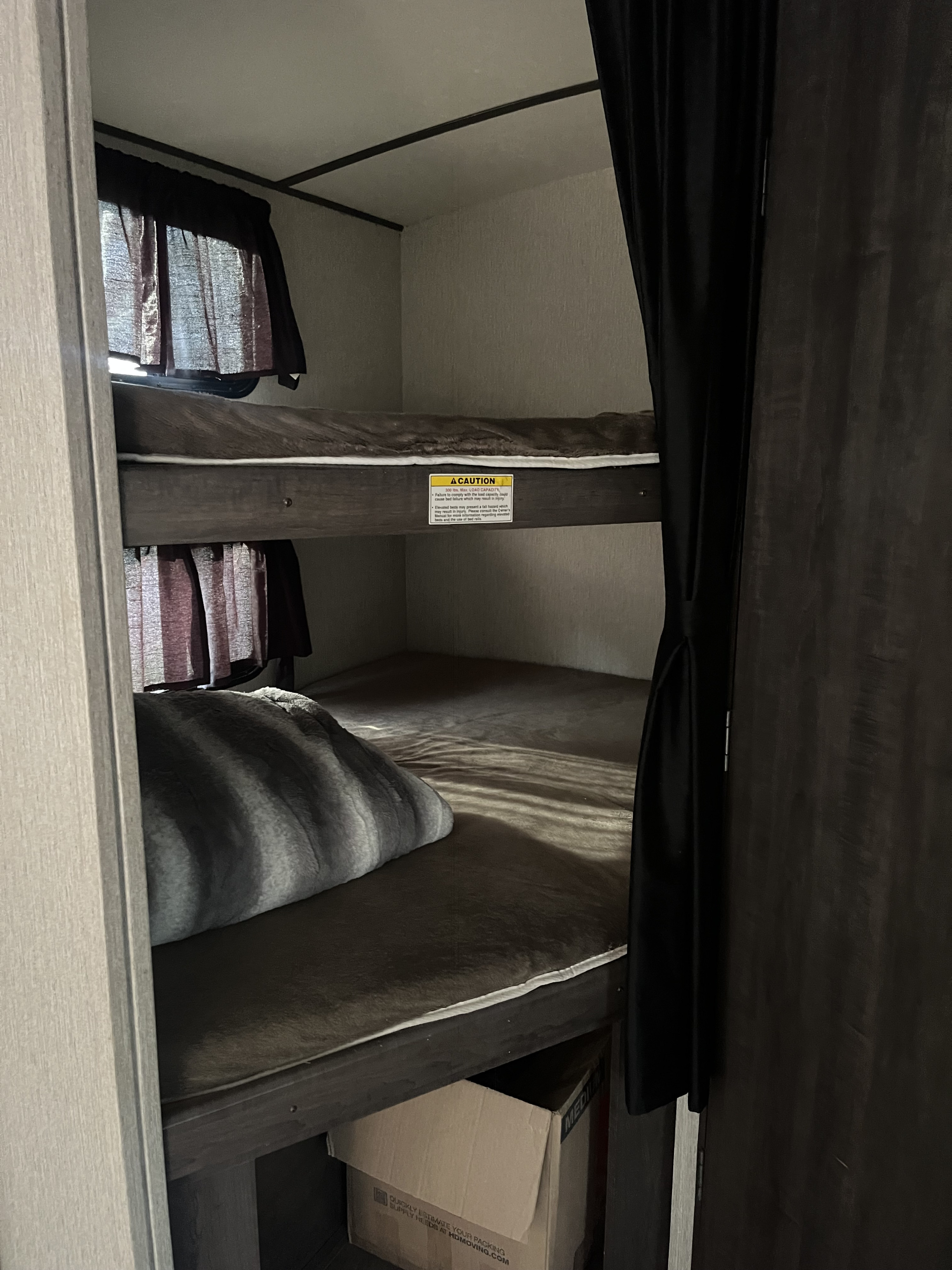 Cozy bunk beds in this RV rental's sleeping area, complete with bedding and privacy curtains, perfect for family travel.. Crossroads RV Sunset Trail Super Lite 2019