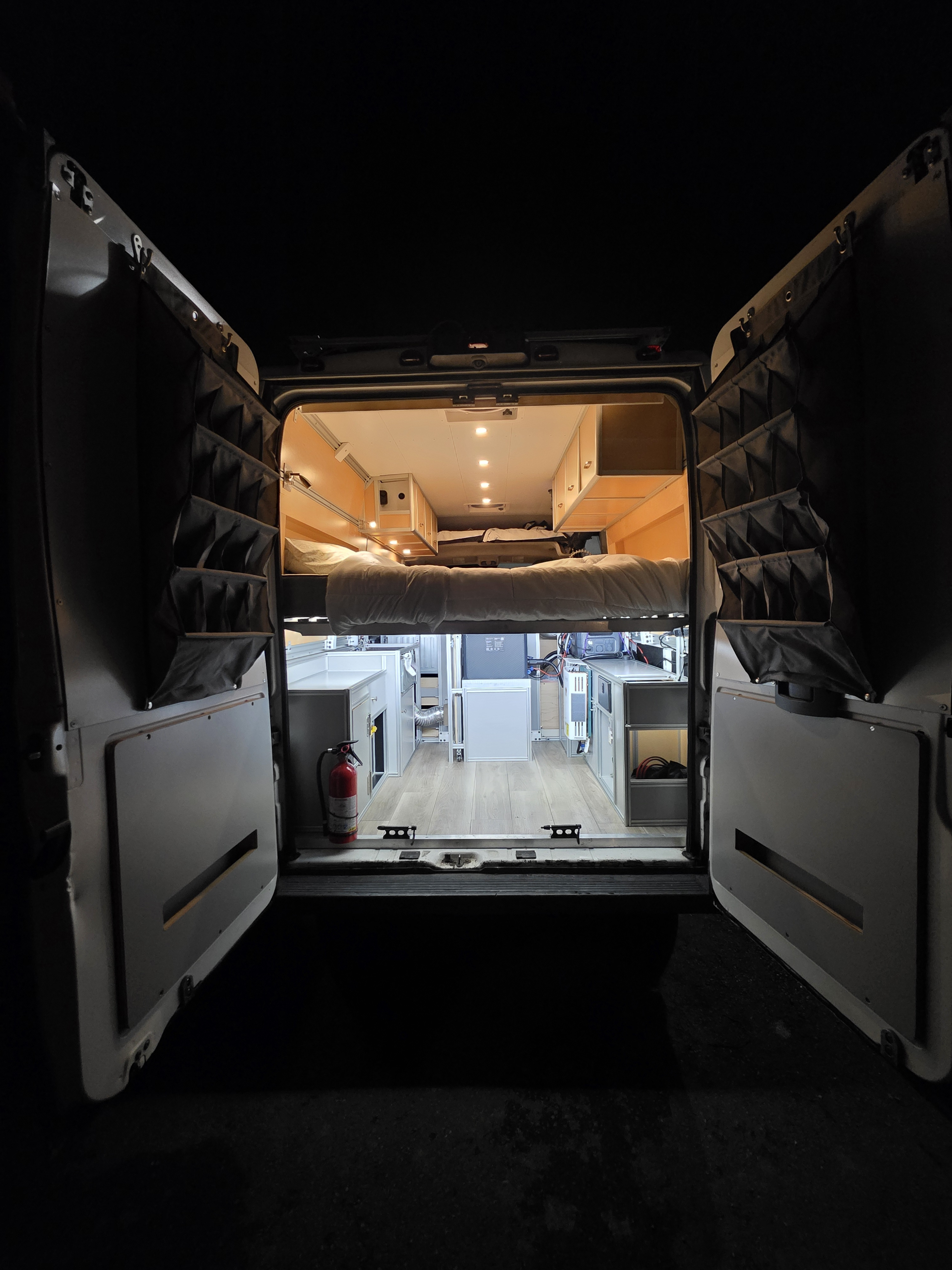 Step into this bright rv rental camper van, revealing a raised bed, cabinetry, and door organizers, perfect for mobile adventures.. Custom Built Avantgarde 2013