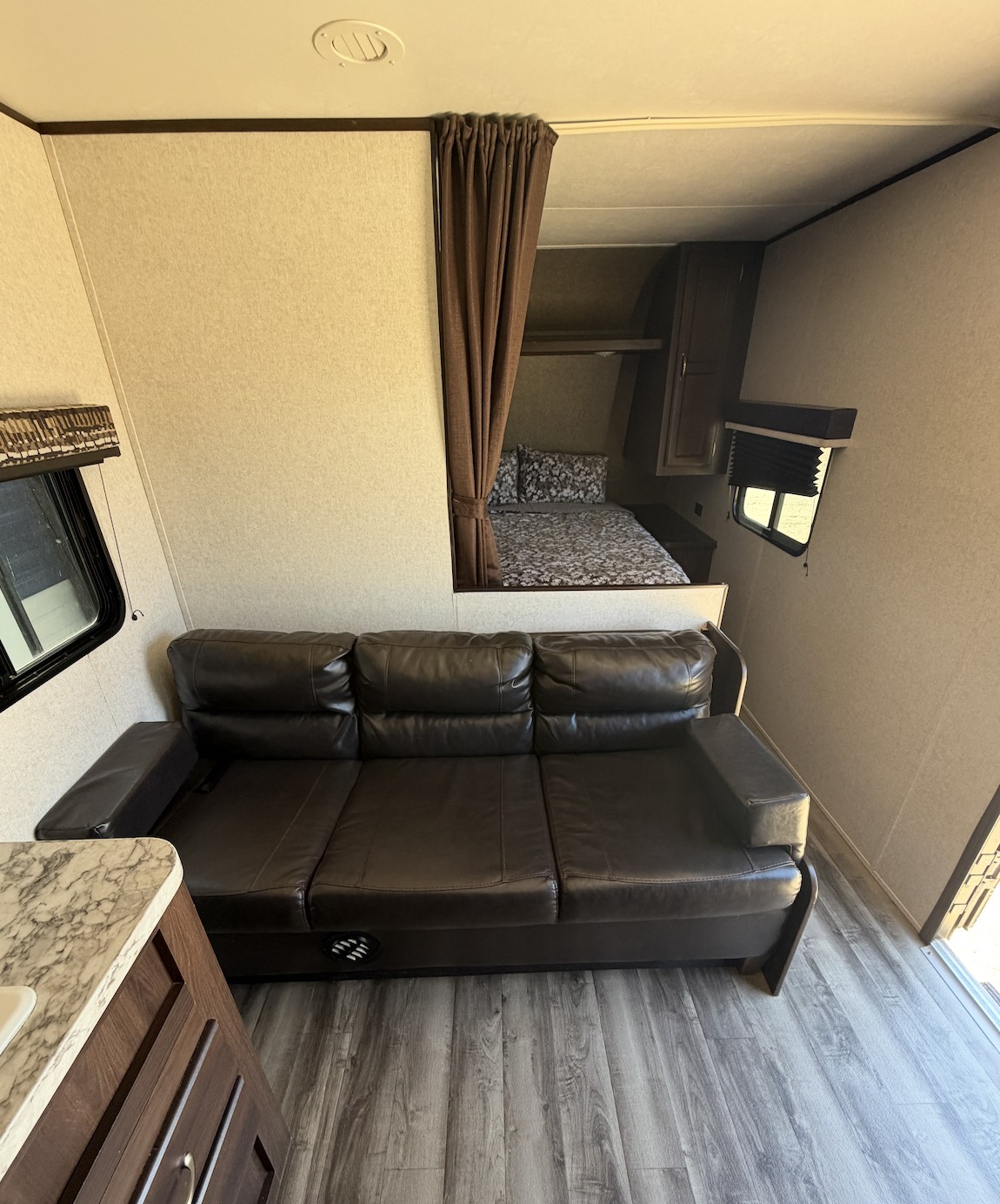 RV rental: Relax on the sofa in this RV's living area, featuring a bed nook with a curtain for privacy.. Jayco Jay Flight SLX 2018