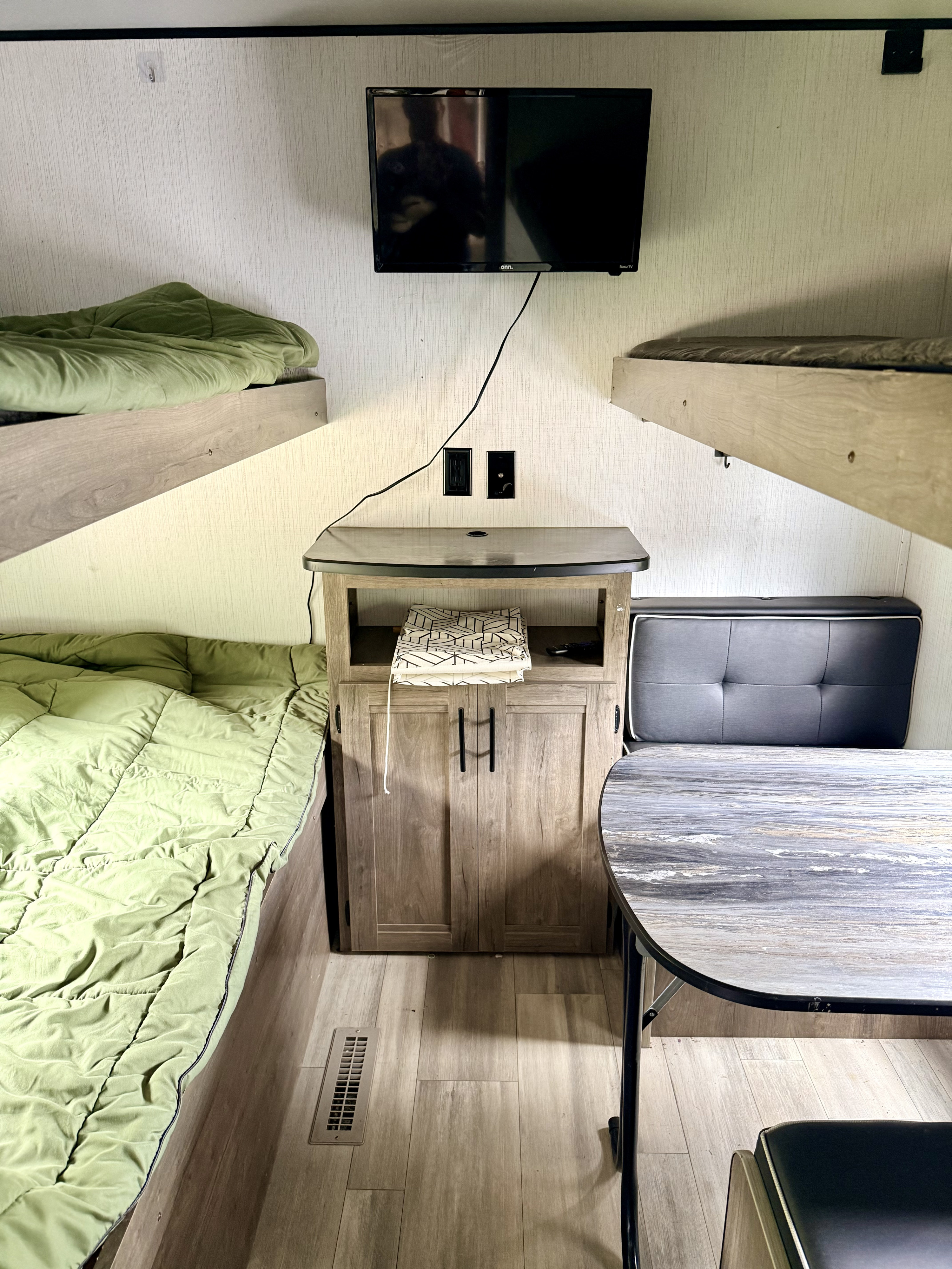 RV rental bunk room with built-in bunks, green bedding, TV, dinette, and wood-look flooring.. Heartland RVs Pioneer 2023