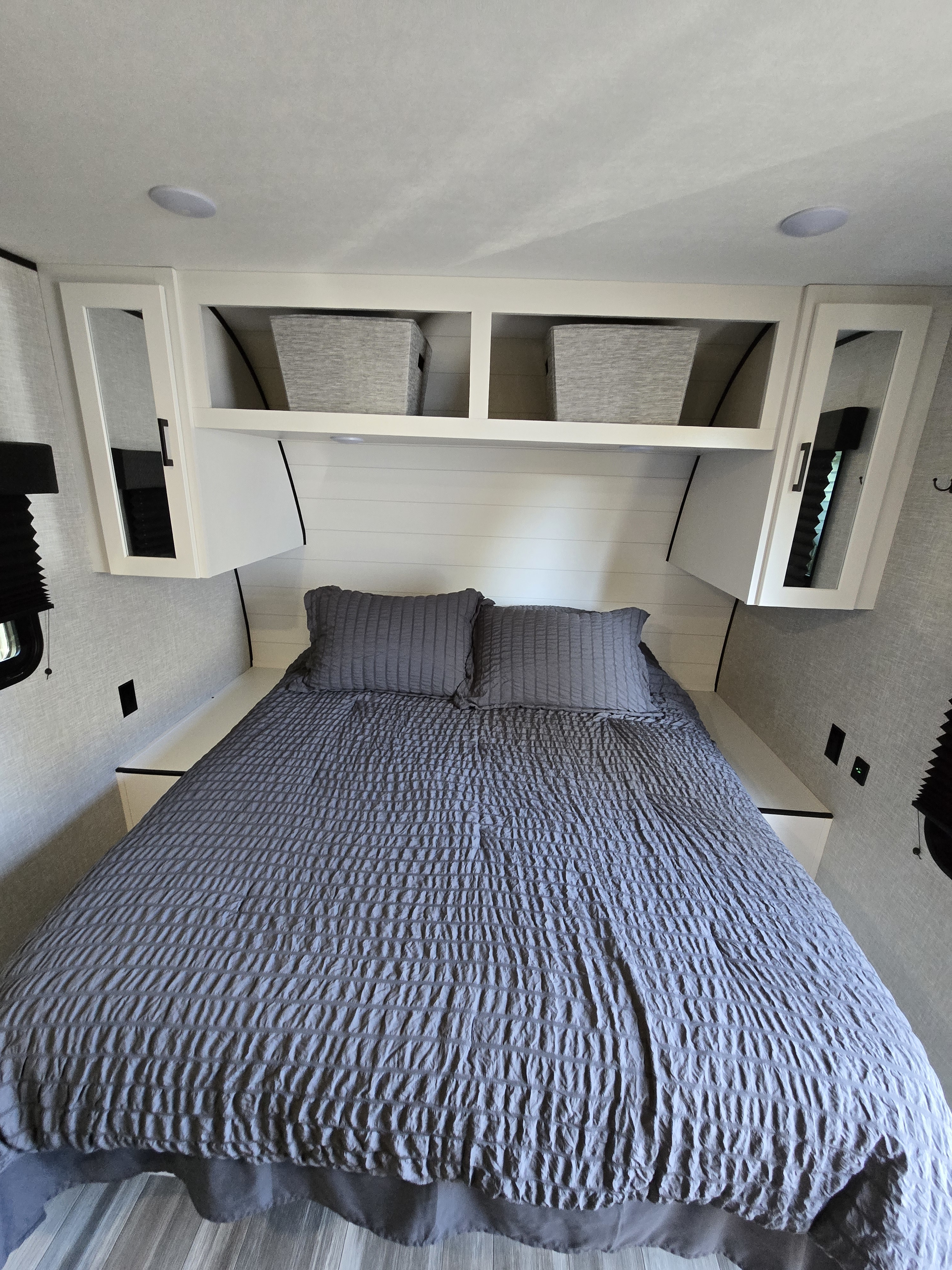 Comfortable RV rental bedroom featuring a neatly made bed with gray bedding, overhead storage, and modern lighting.. Jayco Jay Flight SLX 2025