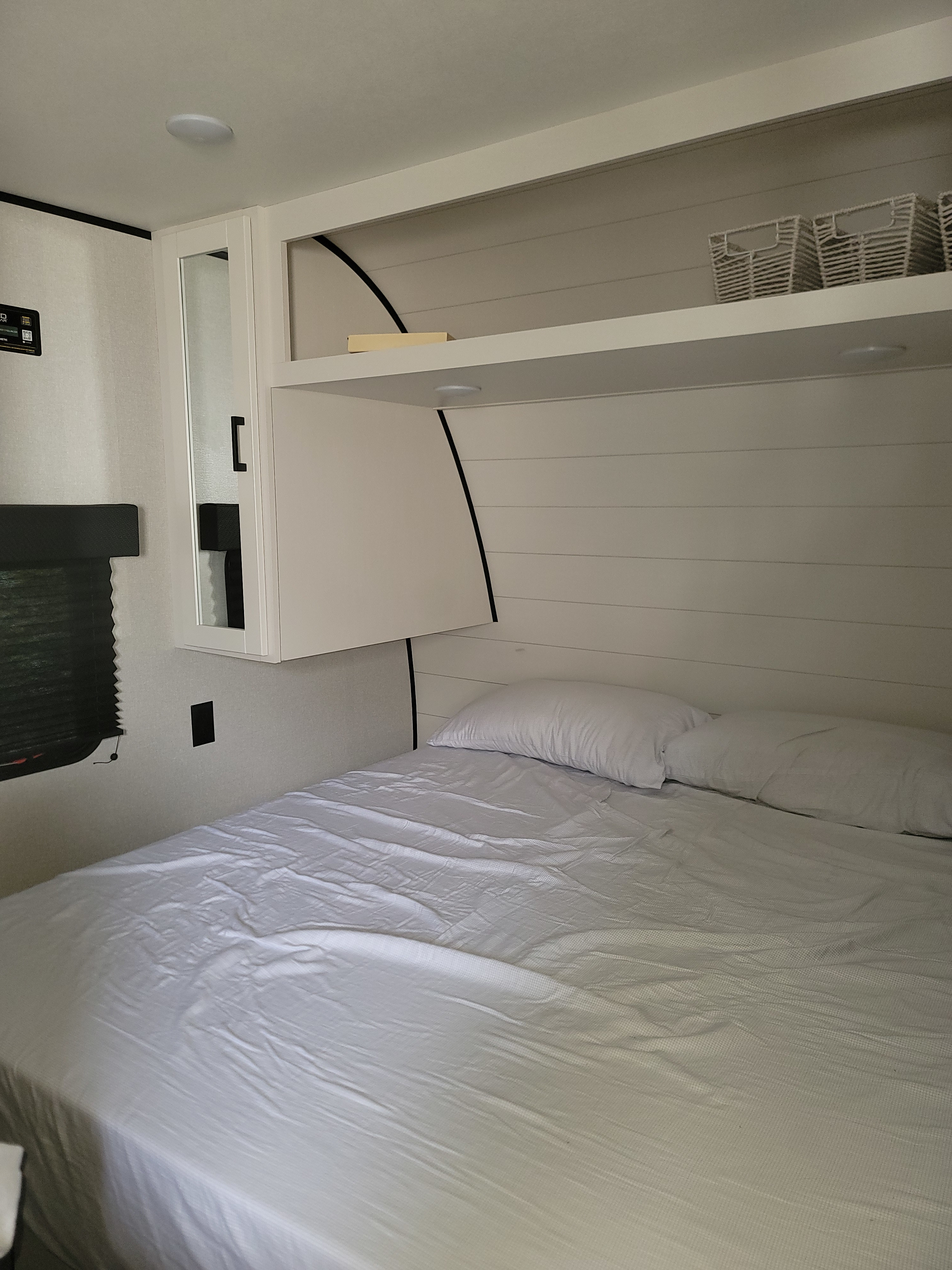 Cozy, modern white bedroom in an RV rental, featuring a comfortable bed, overhead storage, and mirrored cabinet.. Jayco 260BH 2026