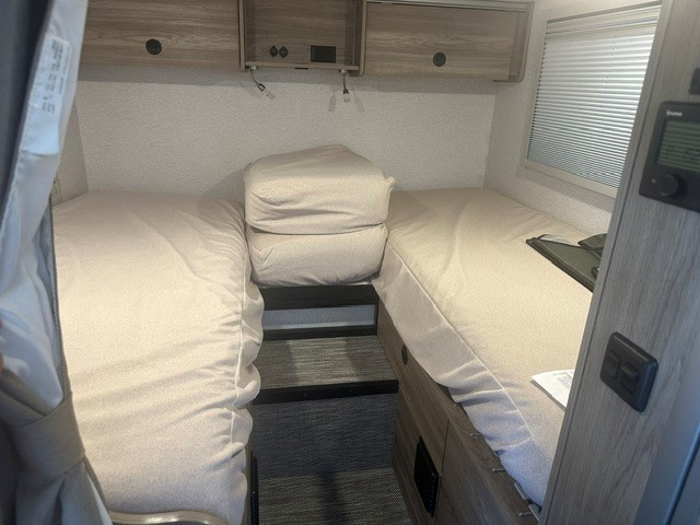RV rental interior features a compact sleeping area with twin beds, overhead cabinets, and a narrow walkway between.. Winnebago EKKO 2026