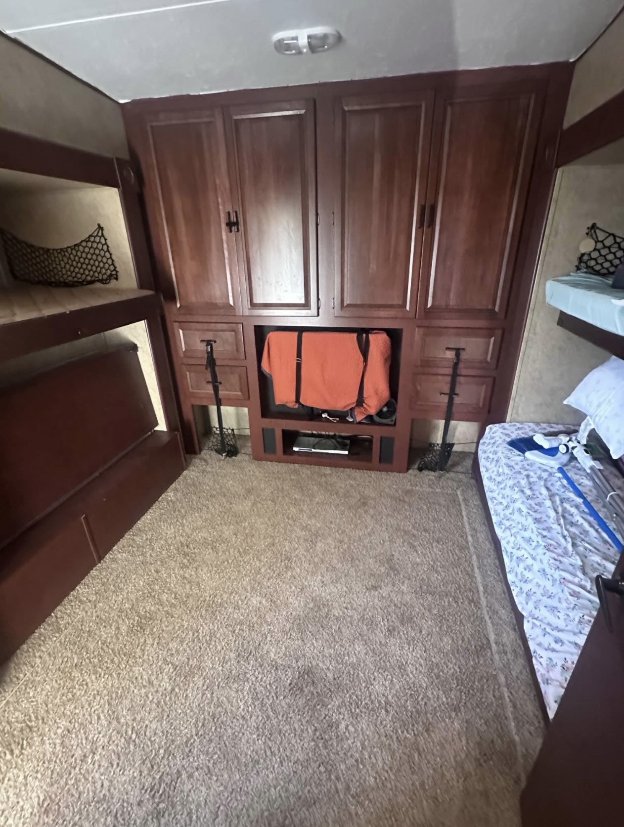 RV rental interior with twin bunk beds, central wooden storage unit, and entertainment console. Carpeted floor offers comfort.. Forest River Sandpiper 2012