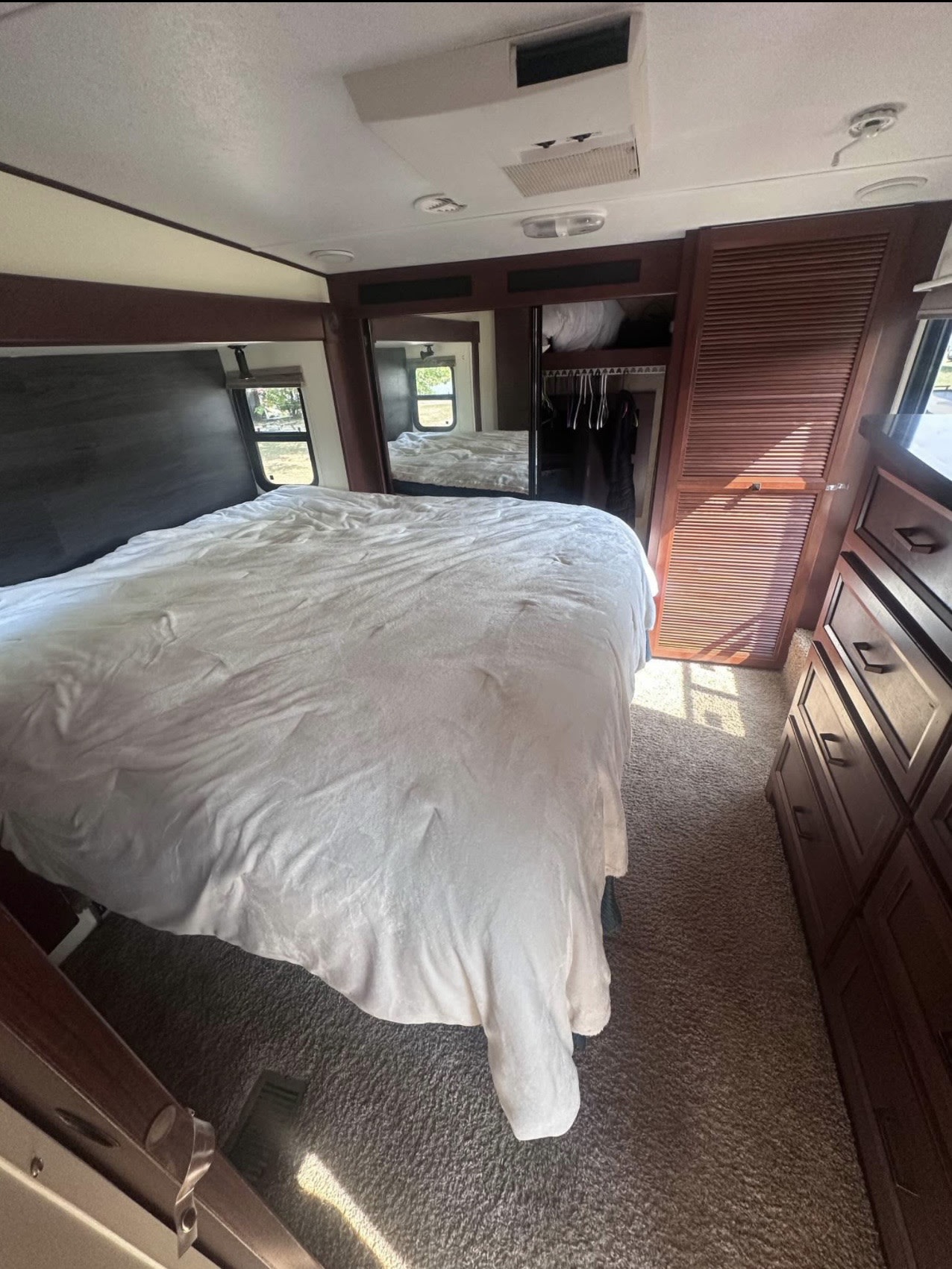 Spacious RV rental bedroom with a comfy bed, windows, and built-in storage. Ideal for travel comfort.. Forest River Sandpiper 2012