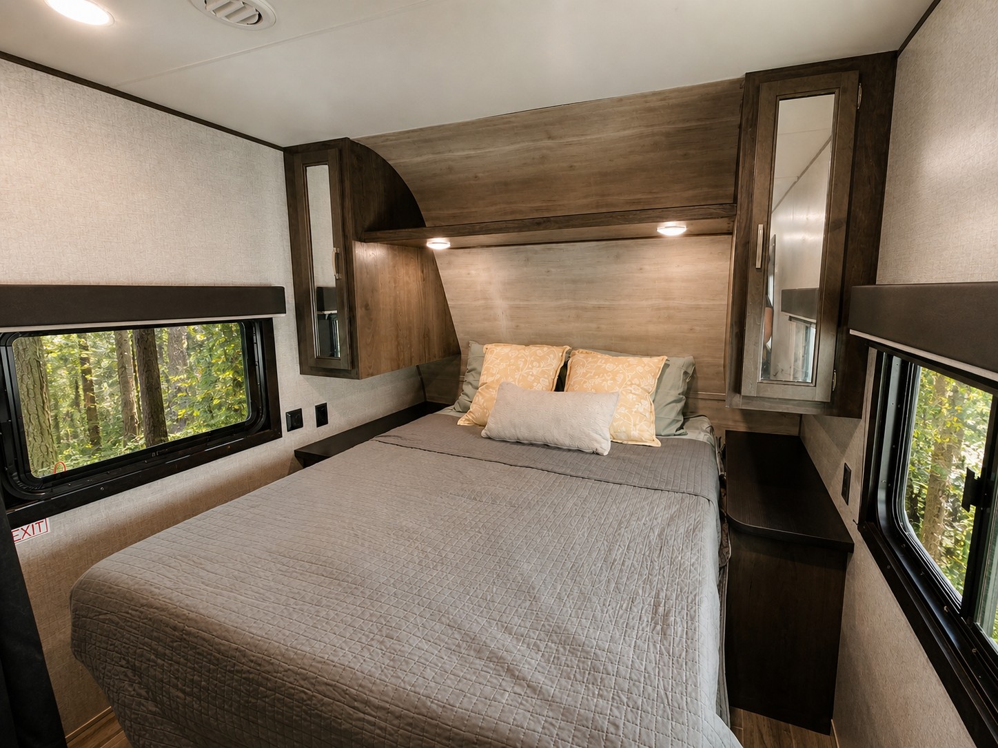 Cozy RV rental bedroom with a gray bed, wood cabinets, and large windows revealing a lush forest view.. Jayco Jay Flight SLX 2021